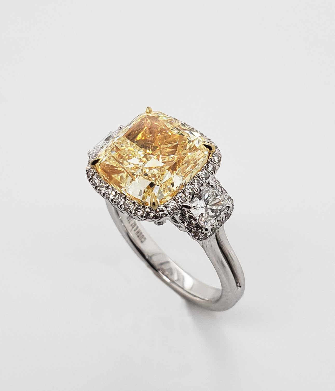 From SCARSELLI, this beautiful statement ring features a 6.02 carat Fancy Yellow Cushion Cut Diamond of VS2 clarity flanked with radiant cut F color diamonds (.20 each) and framed in round white diamonds.  See pictures for detailing and for the GIA