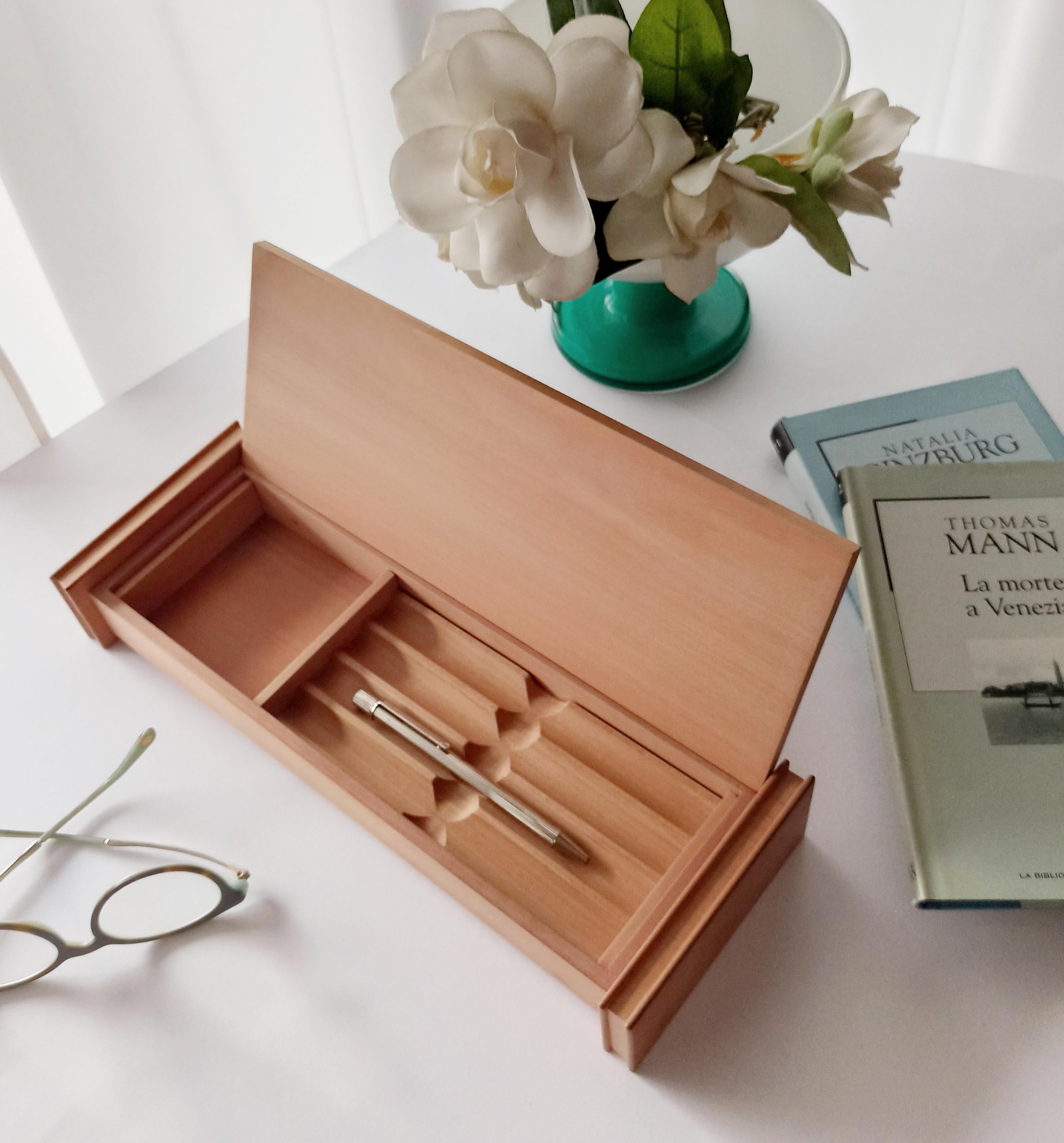Pen box made of pear wood with a minimalist design. Pear wood has a pinkish color and is distinguished by fine, delicate grain that makes it elegant. The construction of this box is distinctive and rich in detail. The short sides consist of 3