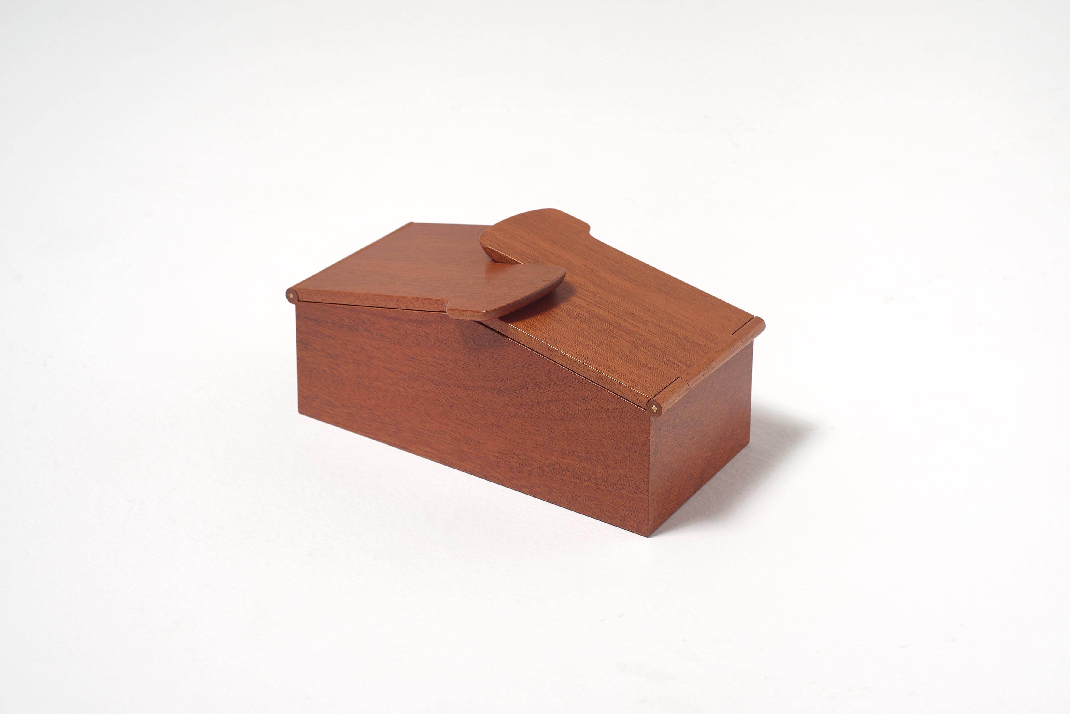 An elegant wooden box with architectural lines, whose lid is made of two parts that meet to complement each other in a delicate embrace.
 
Dimensions: 27 W x 14.5 D x 12 H cm.