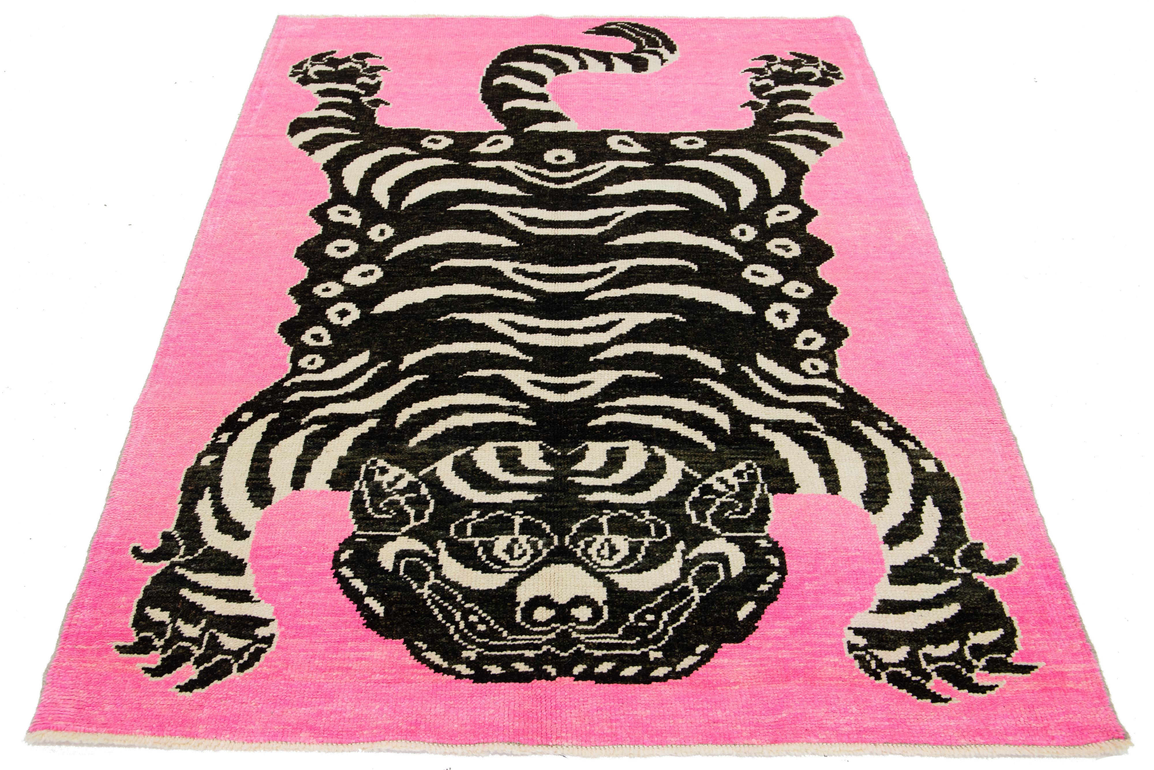 This room-size wool rug from Turkey showcases a stunning tiger pictorial design with a pink backdrop and accents in black and beige. It is meticulously handmade with attention to detail.

This rug measures 4'10