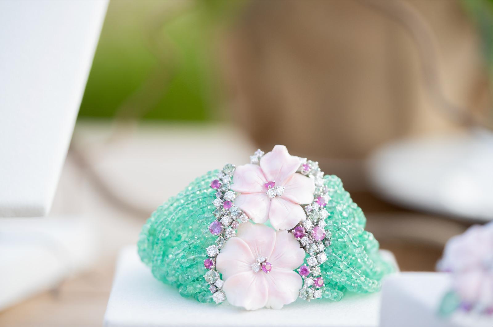 Introducing the exquisite FIORINA EMERALD BRACELET, a masterpiece crafted with white gold, adorned with lustrous emerald beads threads, and embellished with delicate pink shell flowers. Each link of this enchanting bracelet features round brilliant
