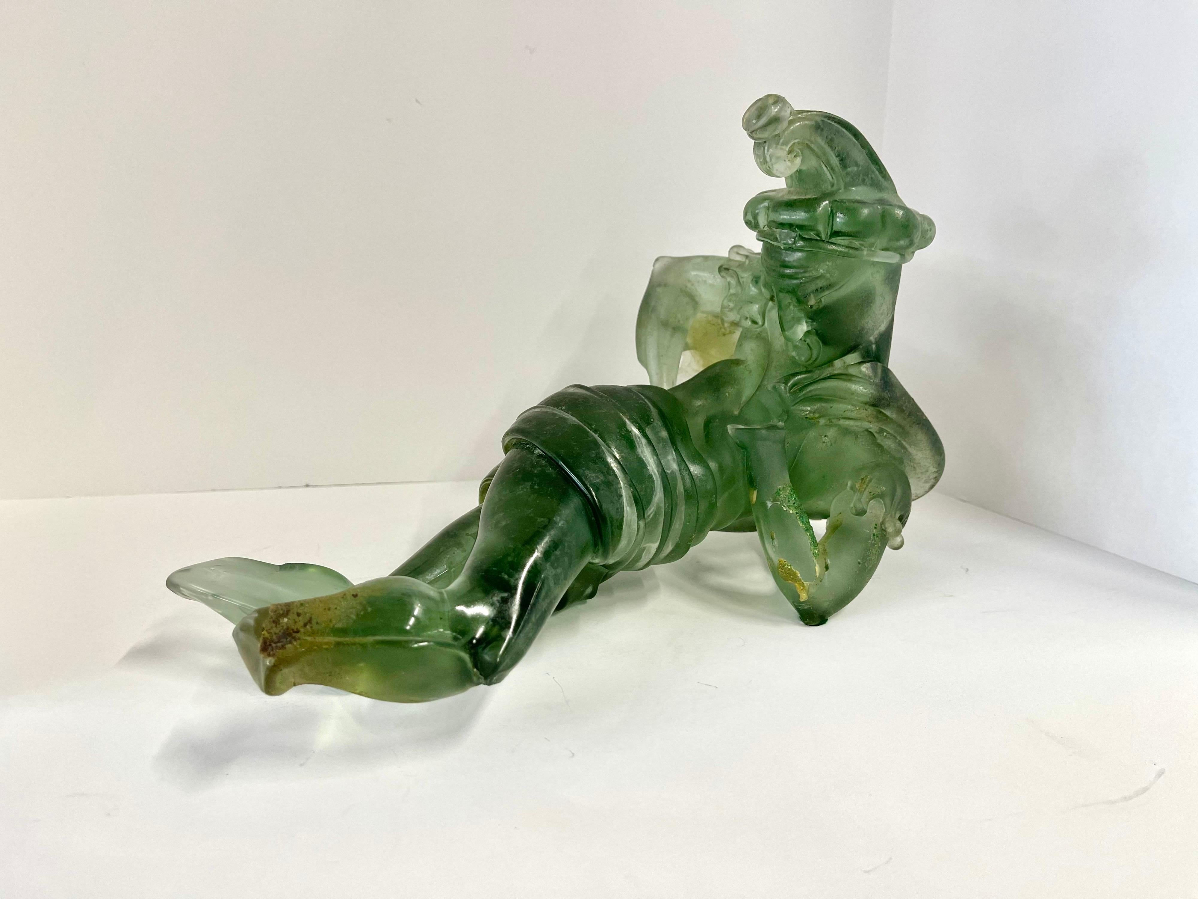 An Italian Murano glass figure of a jester in a Scavo finish attributed to Ermanno Nason for Cenedese. Typical of his figural forms there are no hands or feet. The inclusions in the glass and surface imperfections are also in the style of his scavo