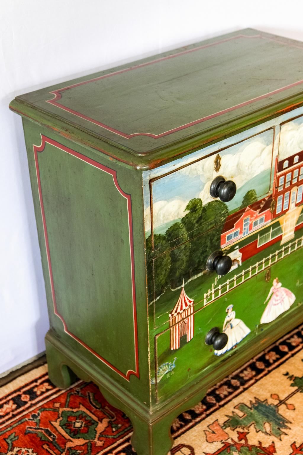 Scenic painted four-drawer chest, this hand painted scene depicts ladies and gentlemen playing croquet on the lawn of an English country manor. There is a mountain landscape in the background.


  