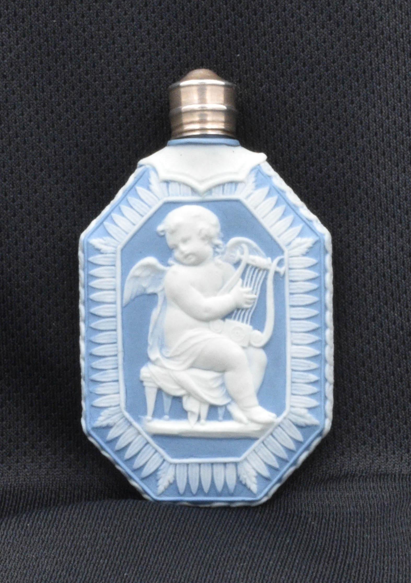 A scent bottle in pale blue jasperware, with original silver CAP and dipper.

Decorated with Cupid playing the lyre, and Cupid singing. The God of Love suggests this was intended as a love-token, a gift given to a young lady by her sweetheart.

.