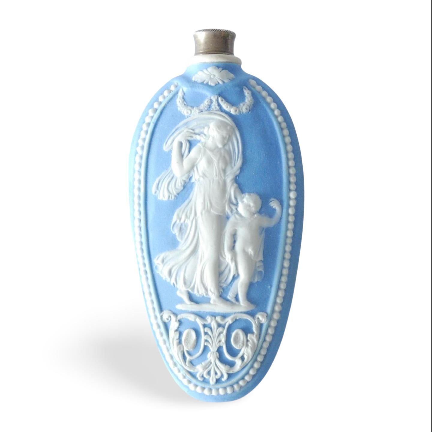 A scent bottle in pale blue jasperware, with original silver lid.

Decorated with Venus and Cupid, as allegories of Night -  the one shedding poppies, the other drawing the veil of stars over her head. 

The God of Love suggests this was intended as