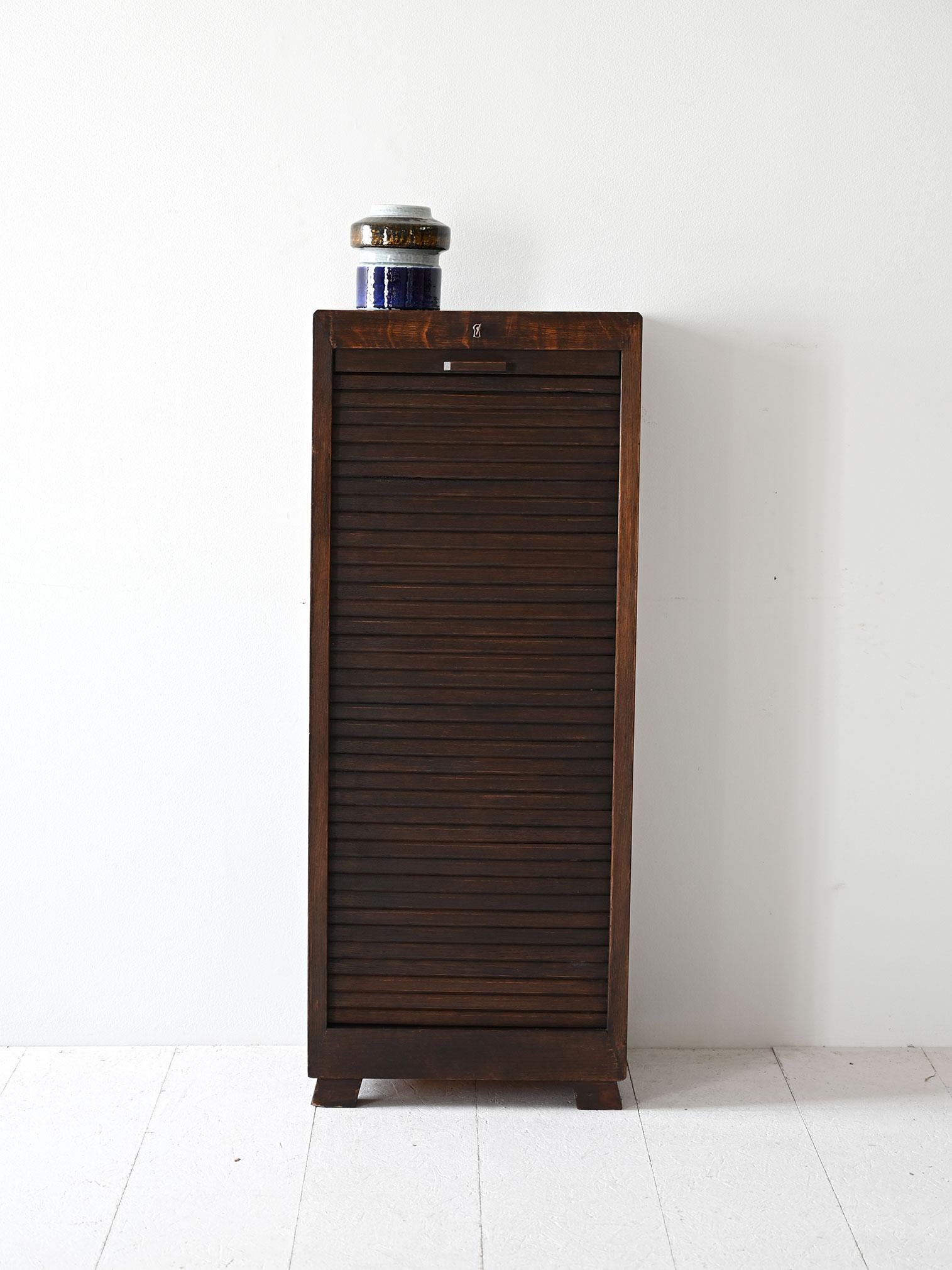 Scandinavian filing cabinet with shutter door and interior divided by pull-out shelves. 

The square lines and dark finish give it a solid, understated look perfect for offices or studios. The compact design allows it to be placed in rooms of