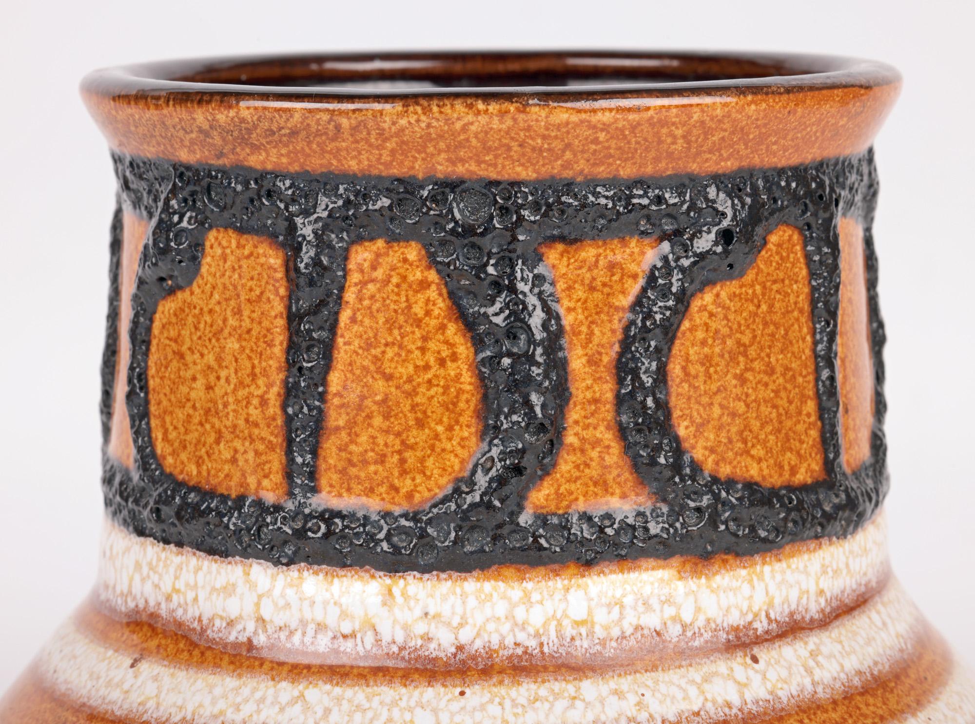 Un élégant vase cylindrique en poterie d'art allemande du milieu du siècle, décoré d'un motif appliqué en lave émaillée par Scheurich Keramik et datant d'environ 1960. Le vase repose sur un large pied rond non émaillé avec une base légèrement en