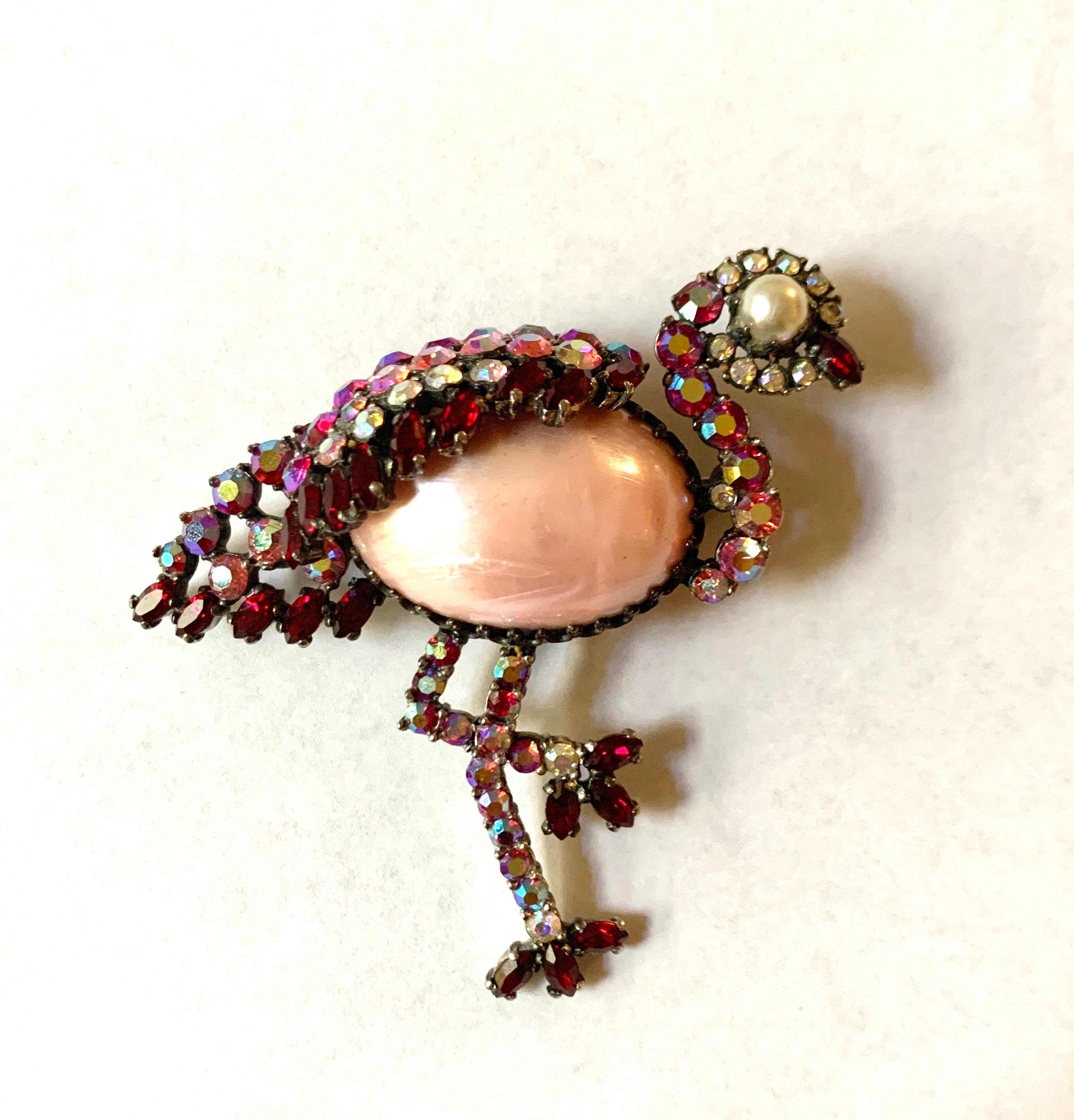 This signed 1960s Schiaparelli jelly belly style rhinestone bird brooch is full of personality and sparkle!  Pink, red, and white aurora borealis rhinestones form a balancing flamingo set in dark silver tone. 

Signed Schiaparelli at back.