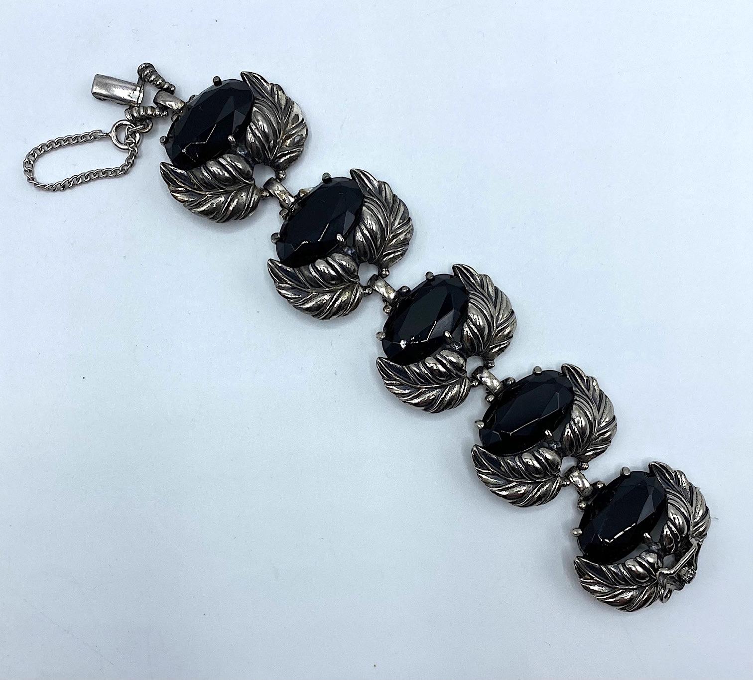 A beautiful 1950s Elsa Schiaparelli bracelet and matching earrings in silver plate foliate design with large oval black crystal stones. The bracelet is 1.5 inches wide and a little over 6.75 inches long. Each clip back earring is a double stone