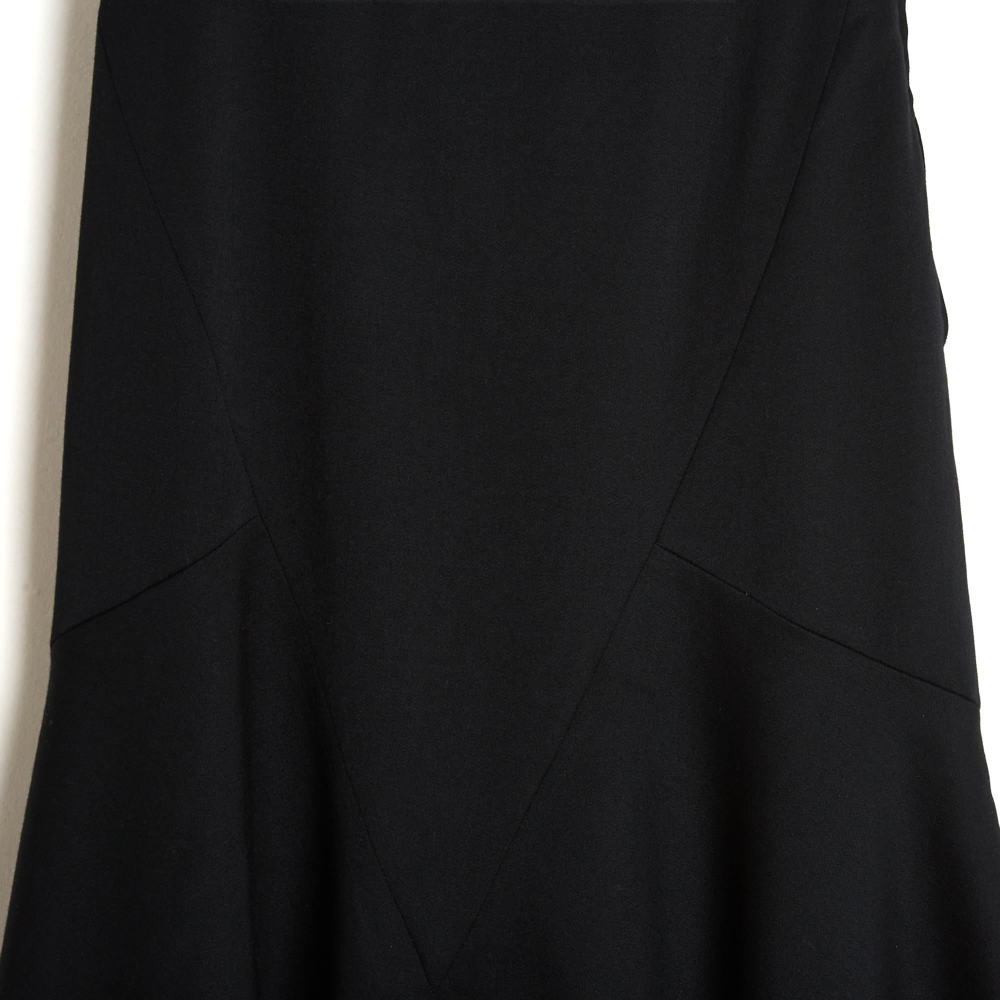 Schiaparelli skirt circa 1990 in slightly satiny black wool twill, length below the knee, fitted cut at the top with a set of yokes and wide godet at the bottom, black satiny canvas lining, closure with a zip and a logo button. No more size label