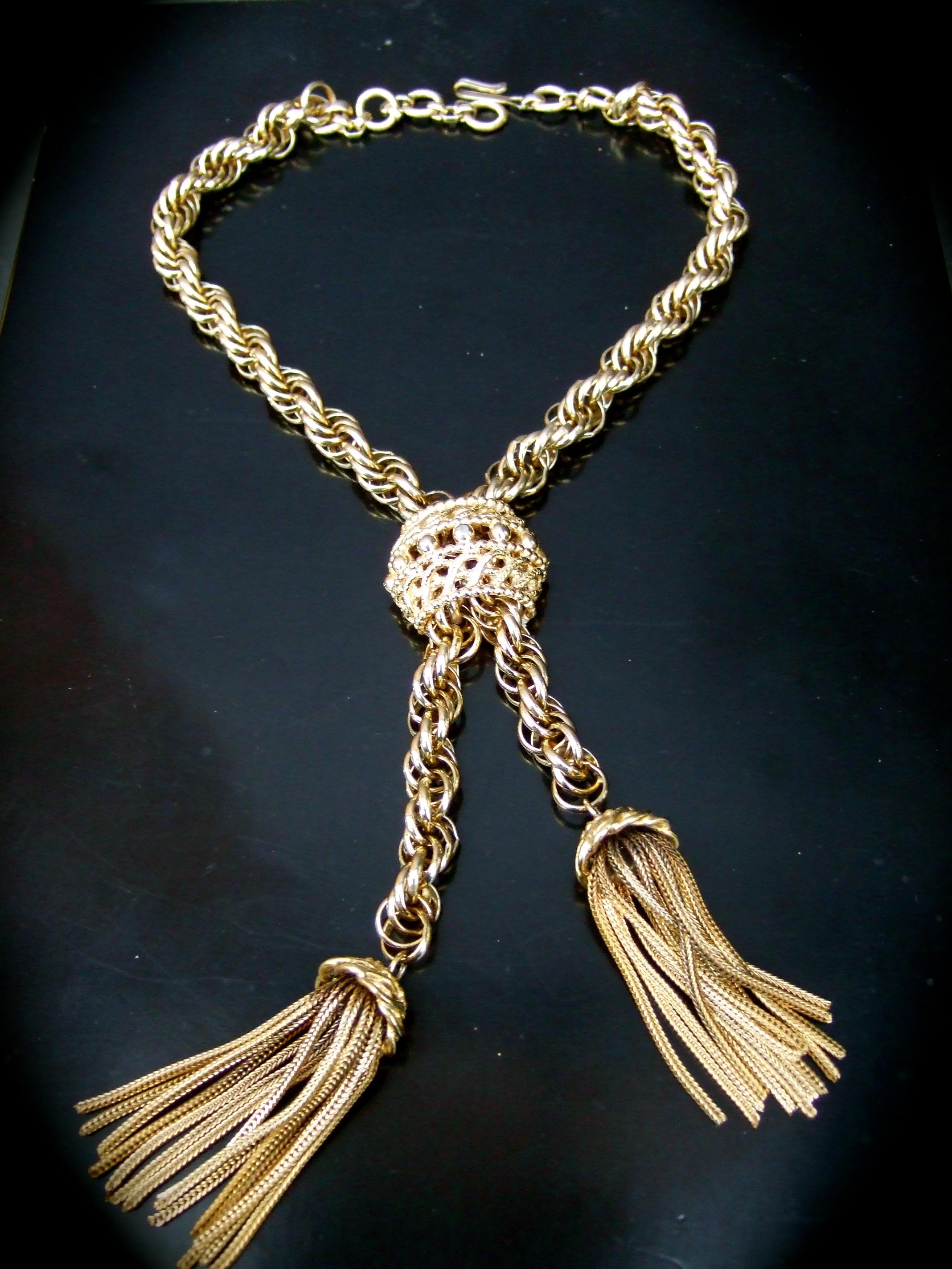 Schiaparelli gilt metal fringe tassel choker chain necklace c 1960
The elegant choker necklace is designed with a sturdy wide braided gilt metal chain
Dangling from the stationary lariat style pendant are a pair of graduated 
fringe tassels 

Makes