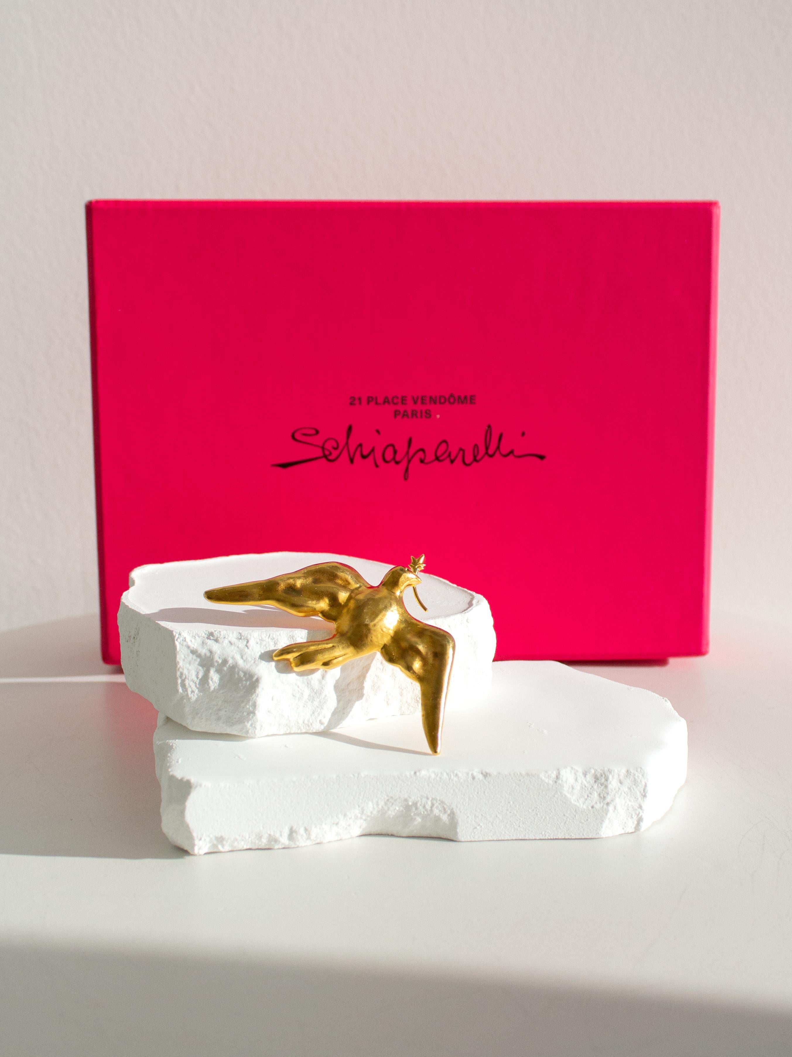 A gilded pewter brooch is in the shape of a Dove carrying an olive branch. Engraved on the back of the wing is the Schiaparelli signature. The XL version of this brooch was worn by Lady Gaga at Joe Biden's inauguration.
Size 3,5