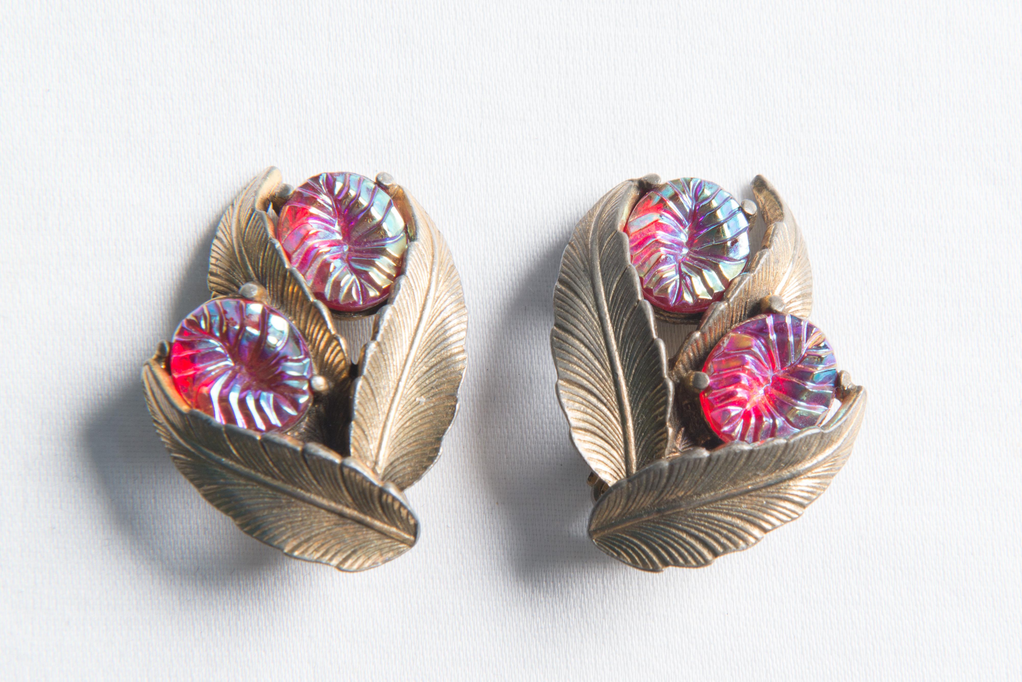 A pair of Elsa Schiaparelli 1940s clip earrings. Each earring has three goldtone leaves and two ruby tone textured jewels.
 