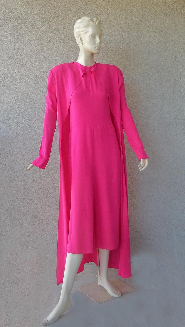 A new Schiaparelli ensemble  inspired by Schiaparelli's prediliction for the shade of hot pink.  Silk tent dress with matching long sleeve coat.  Dress has concealed zip closure at back.  Coat has round neckline with single hook neck closure.  Long