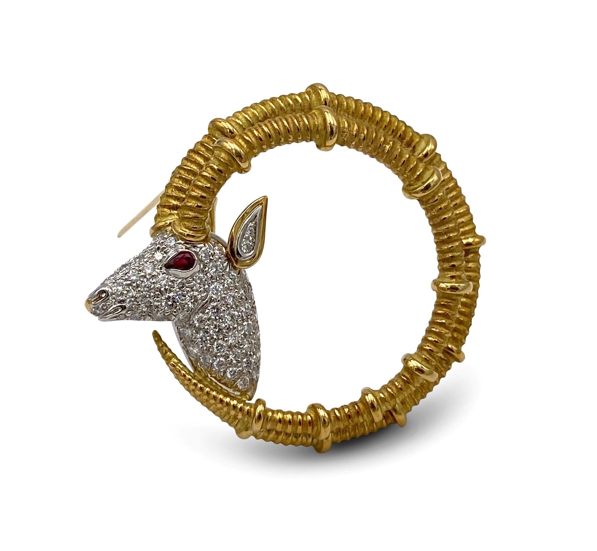 Iconic Ibex ram head pin designed by Jean Schlumberger for Tiffany & Co. The pin is crafted in 18 karat yellow gold with platinum and set with an estimated 0.80 carats of round brilliant cut diamonds (E-F color, VS clarity) and adorned with a ruby