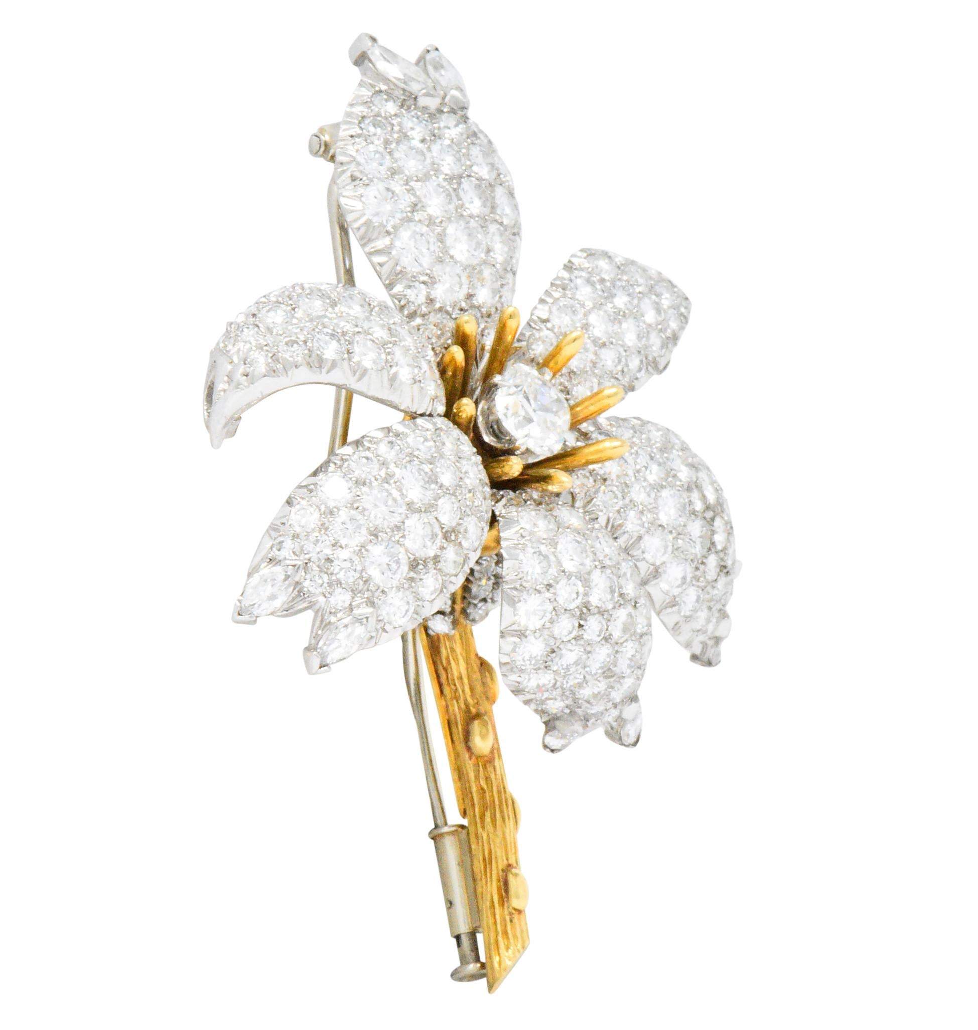 Designed as a dynamically formed flower with pavè diamond petals, polished gold stamen extensions, and a cluster of deeply engraved foliate

Stamen centers a cushion cut diamond weighing approximately 0.80 carat, G color with VS clarity

With round