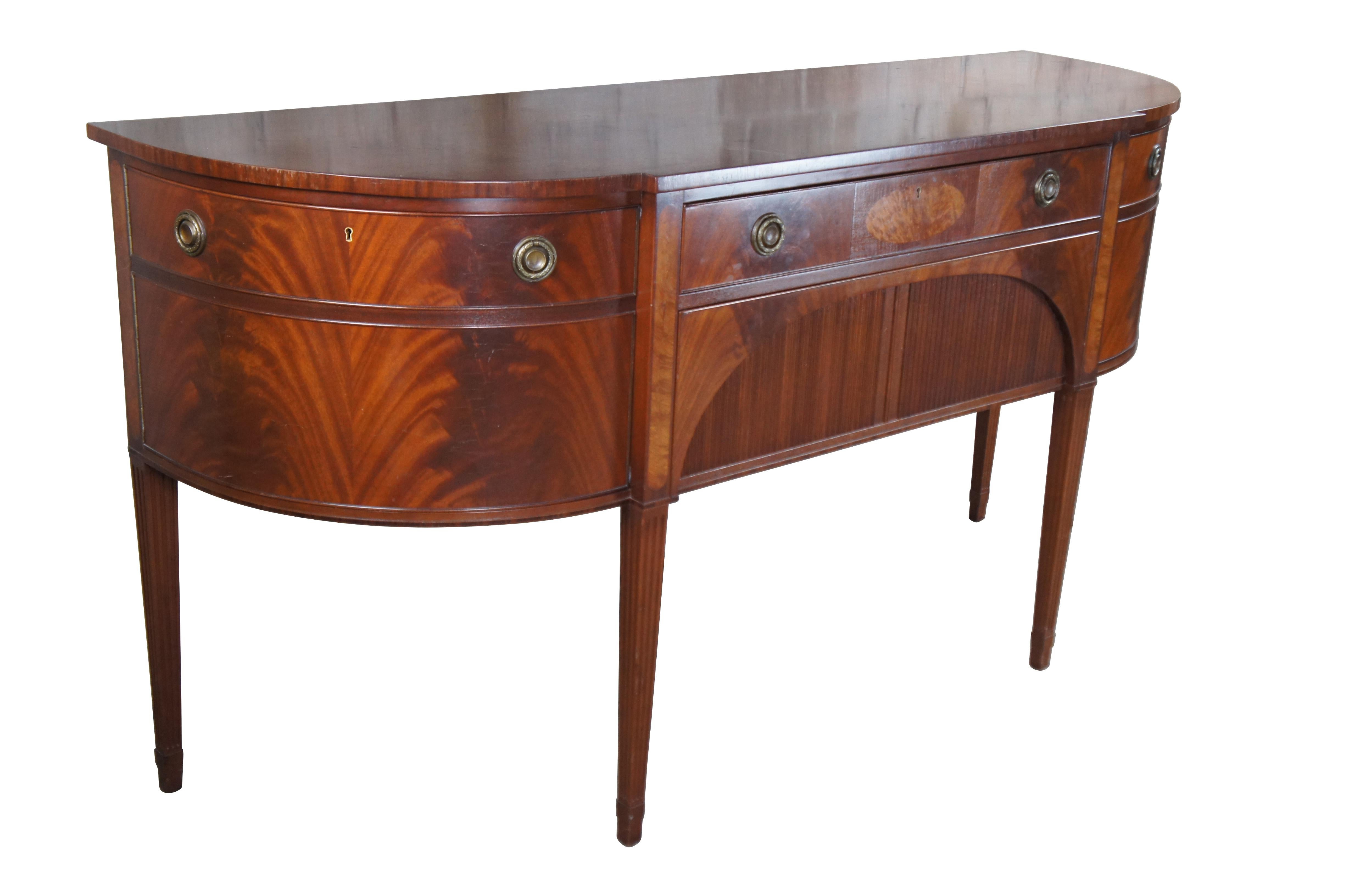 A beautiful Hepplewhite style sideboard or server by Schmieg & Kotzian, circa 1930s.  Features a demilune form made from mahogany with a breakfront center having two graduated hand dovetailed drawers.  The large lower drawer has an arched and