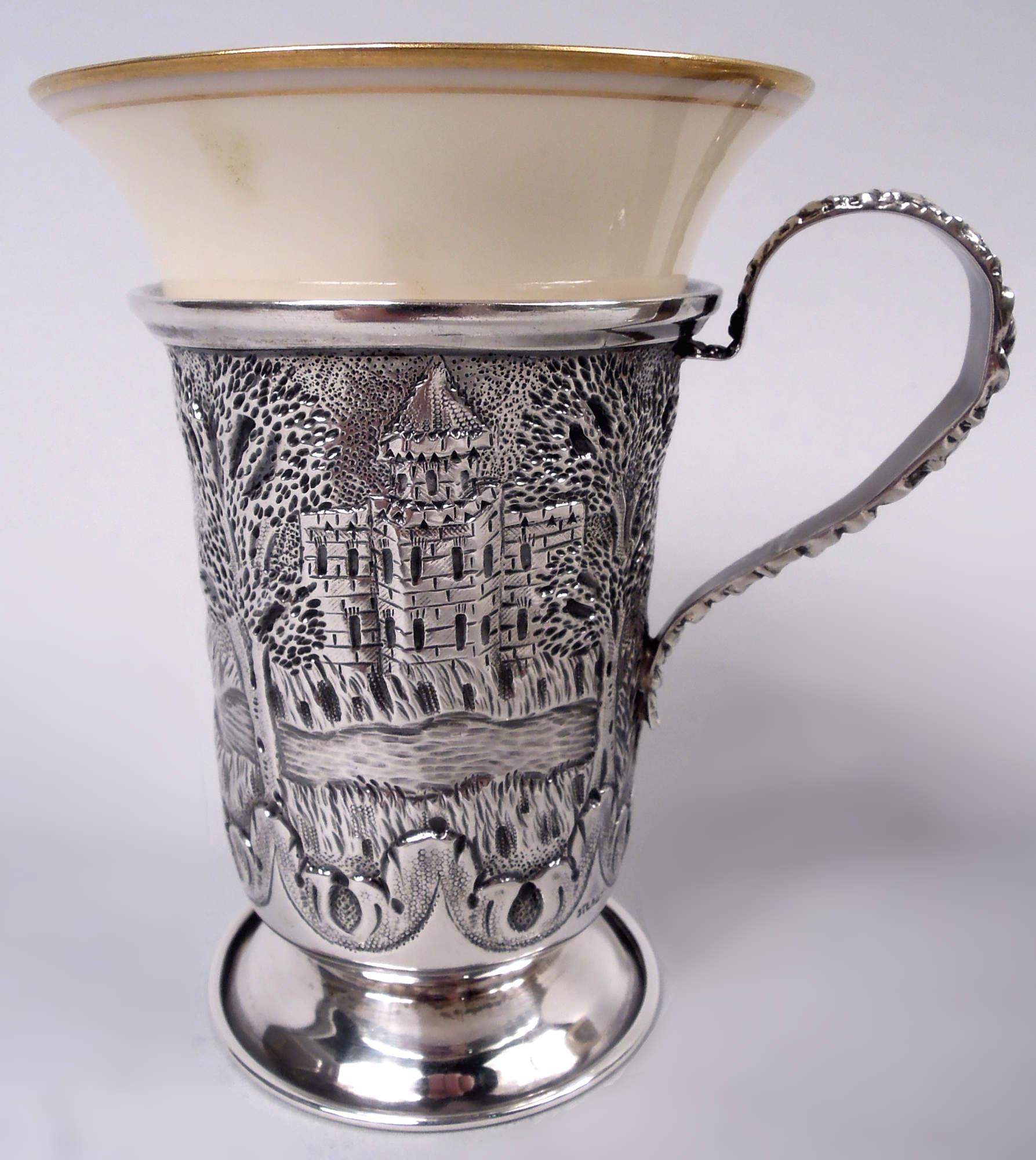 Paire de porte-démitasses en argent sterling de l'époque édouardienne. Fabriqué par Heer-Schofield Co. à Baltimore, vers 1910. Chacun : Coupe haute et effilée sur pied uni et écarté ; anse en boucle haute avec fleurs moulées de style repoussé. Scène