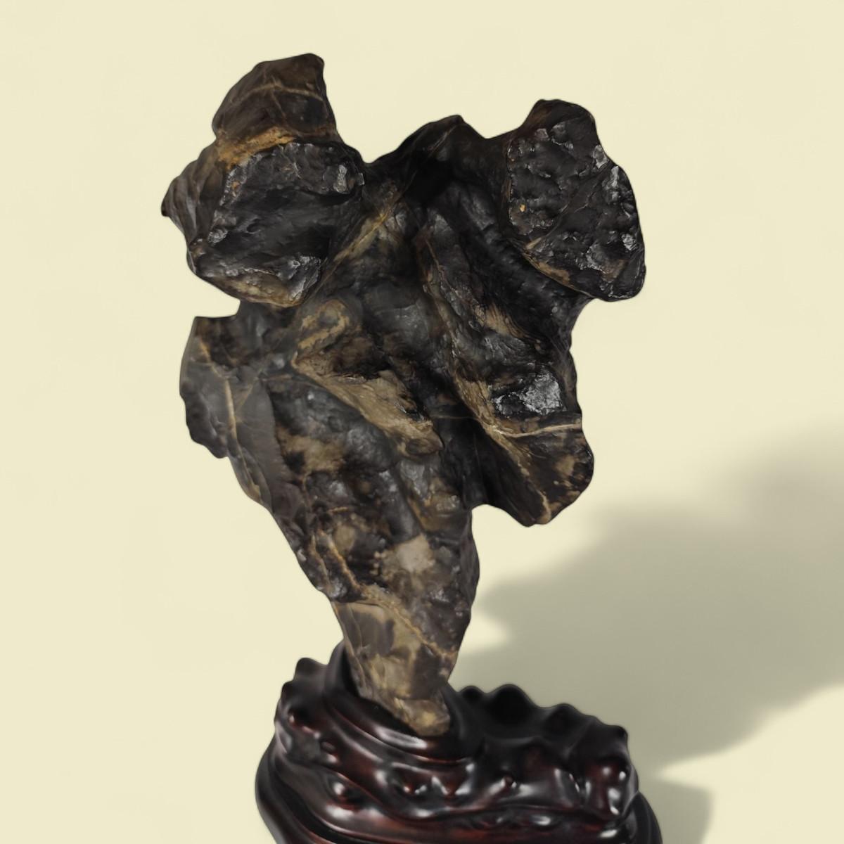 An exceptional scholar's rock lingbi (灵璧石), traditionally intended for Chinese scholars, on a very elaborate Qing period wooden base. It is presented with the larger end above the smaller, a position known in China as yun tou, yu jiao or 'head in
