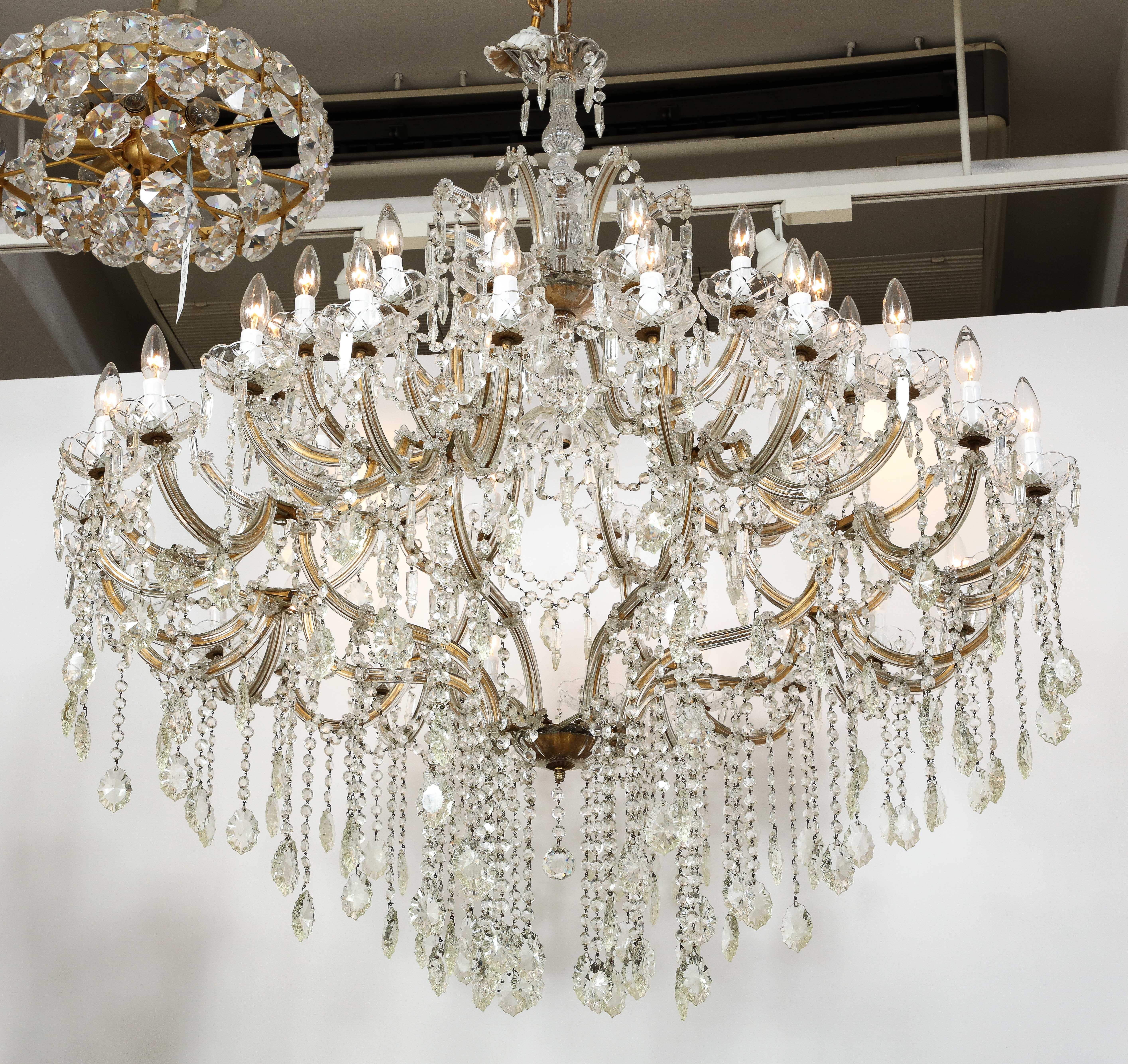 Louis XVI, Hollywood Regency chandelier dripping with faceted crystal chain and prisms. Chandelier features 31 lights, wired for use in the USA.