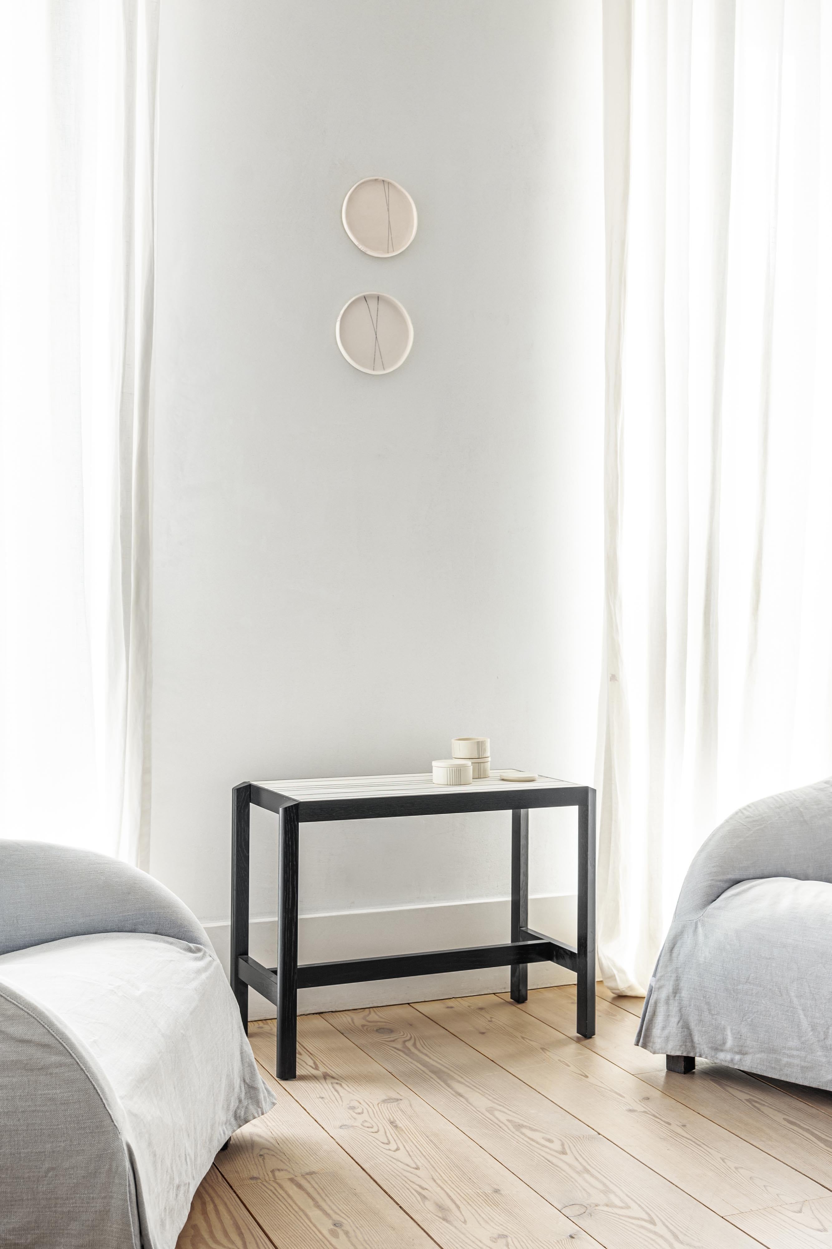Console table L
in solid wood with open-pore lacquer finish in .46 black, ceramic tile insert.

The JUSTE console table is a luxurious statement piece. The top consists of a single oversized ceramic tile, custom-made in Italy. Resting within its