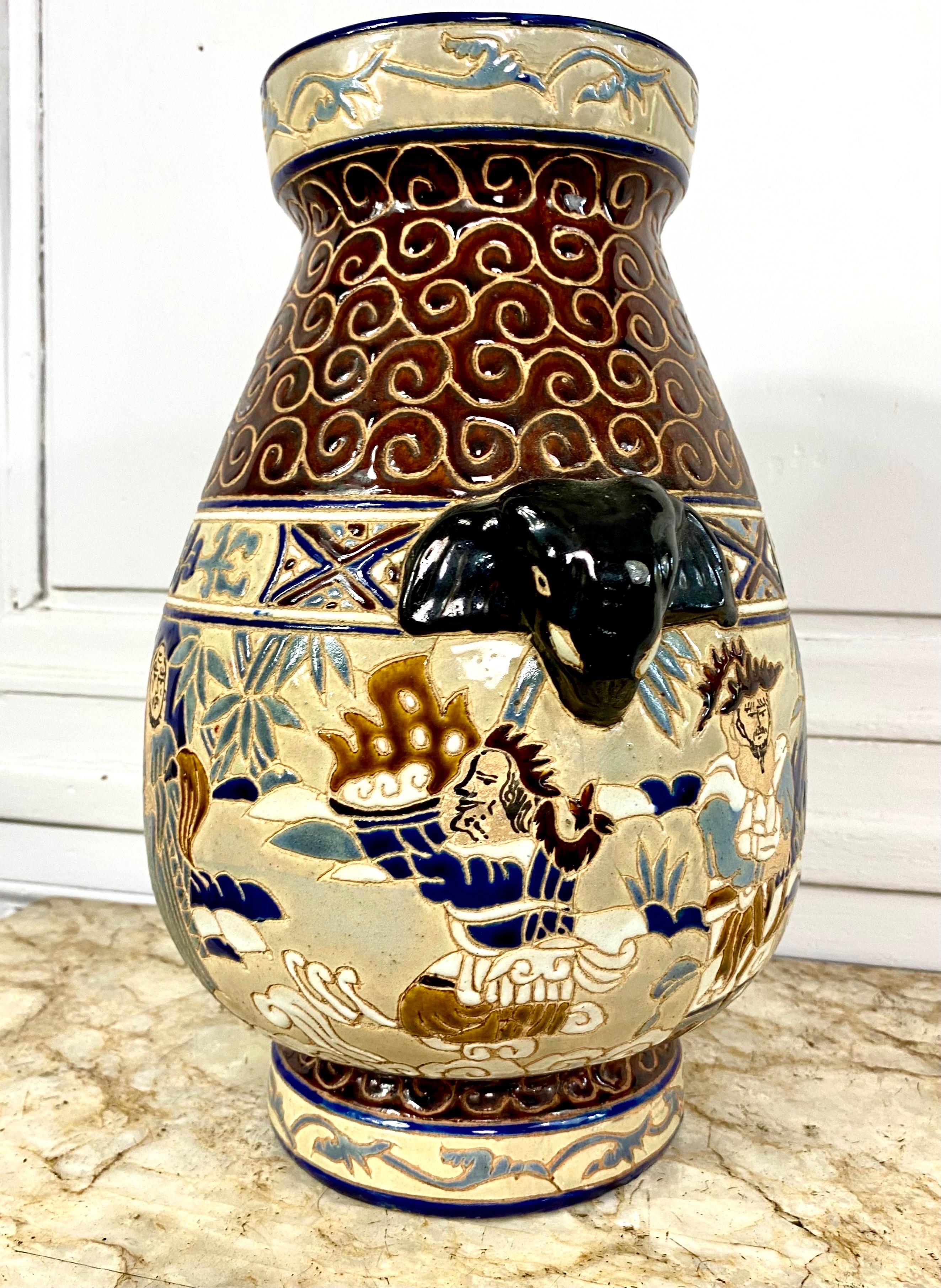Vase en céramique émaillée de l'école Bien-hoa, décoré de six sages de la tradition taoïste. Les poignées sont en forme de têtes d'éléphants émaillées noires. La partie supérieure du vase est en émail brun décoré de rinceaux. La marque sous le vase,