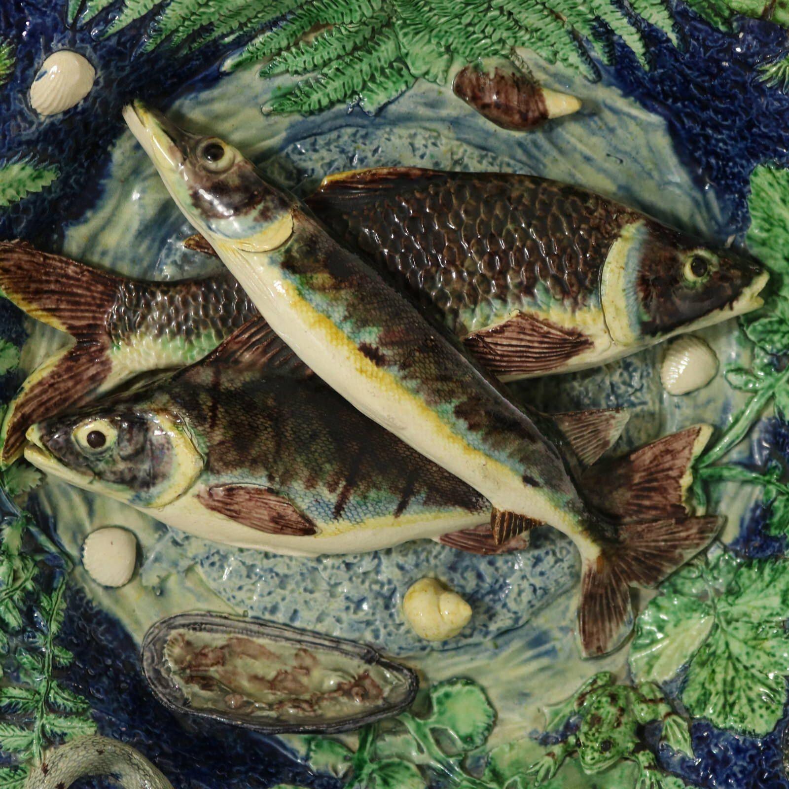 Plato de pared de mayólica de la Escuela de París en el que aparecen tres peces (lucio, perca y carpa), una serpiente, un lagarto, una rana, conchas, una polilla y hojas. Coloración: predominan el azul cobalto, el verde y el marrón. Probablemente