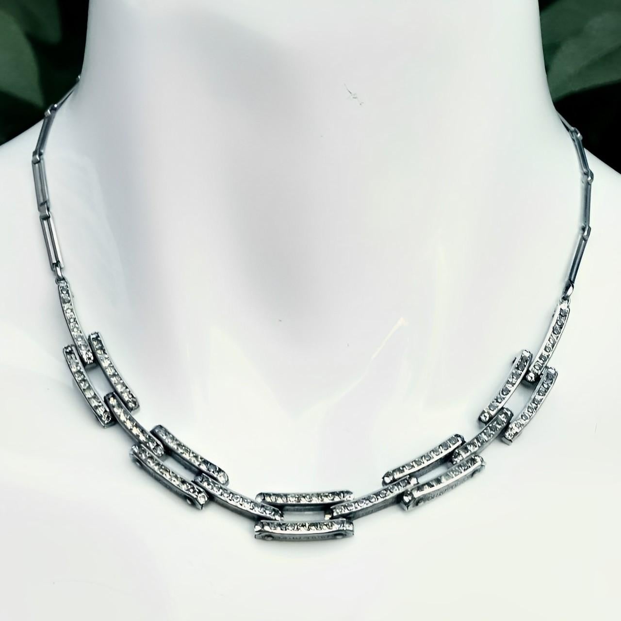 Schreiber & Hiller stylish Art Deco silver tone link necklace and bracelet set, featuring channel set rhinestones and ornate metalwork. There are nine rhinestones making up each link. The clasps work well.

The necklace is length approximately