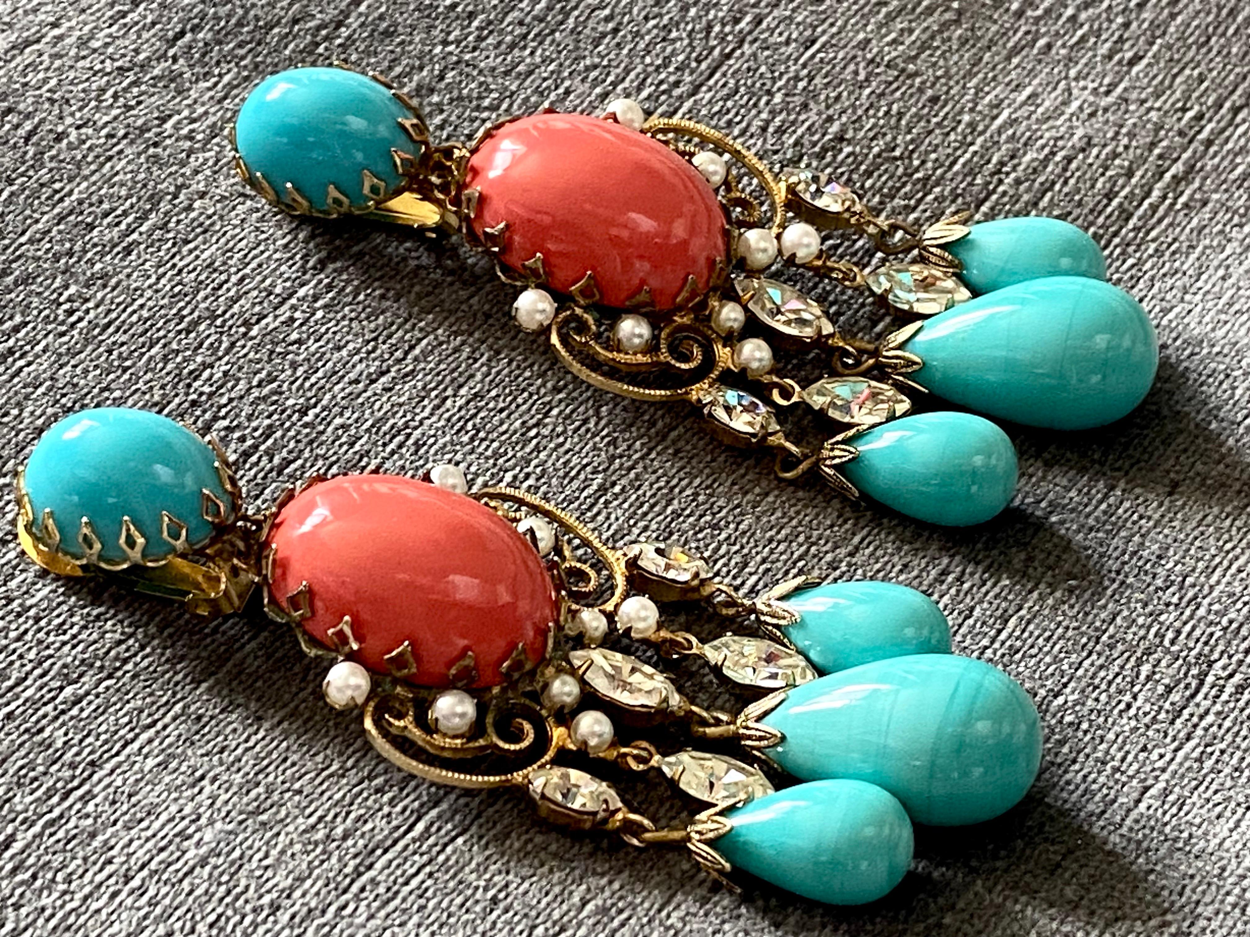 An elegant and rare large pair of chandelier earrings by Schreiner of New York. Each hand made earring is comprised of gold plated fancy wire scrollwork and set with a large glass coral and smaller turquoise glass cabochon. Additionslly, there are