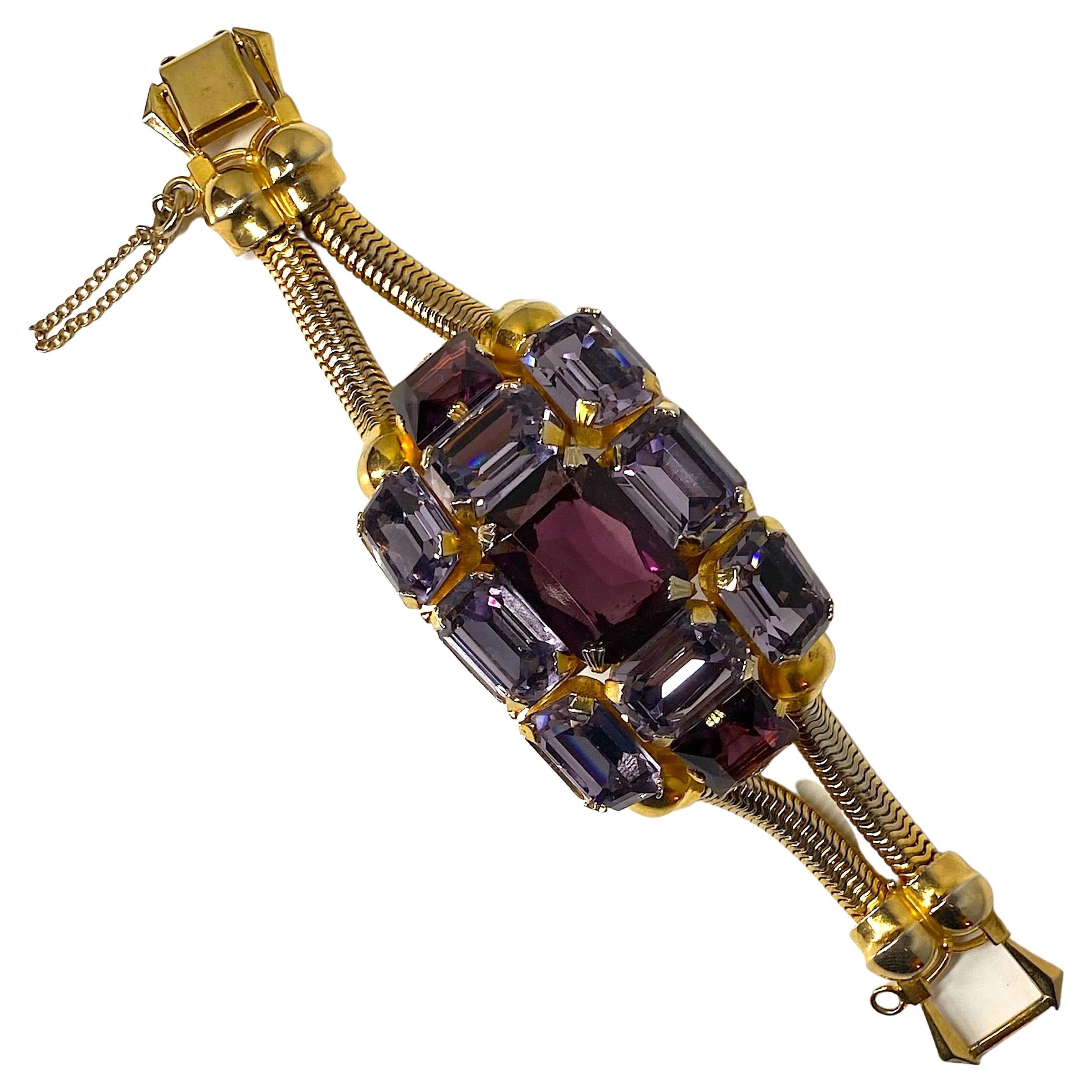 A truly stunning and eye catching 1950s bracelet attributed to the premier rhinestone company of Schreiner. The center part of the bracelet is curved to sit on the wrist and is comprised of two square and on large rectangular center purple crystal