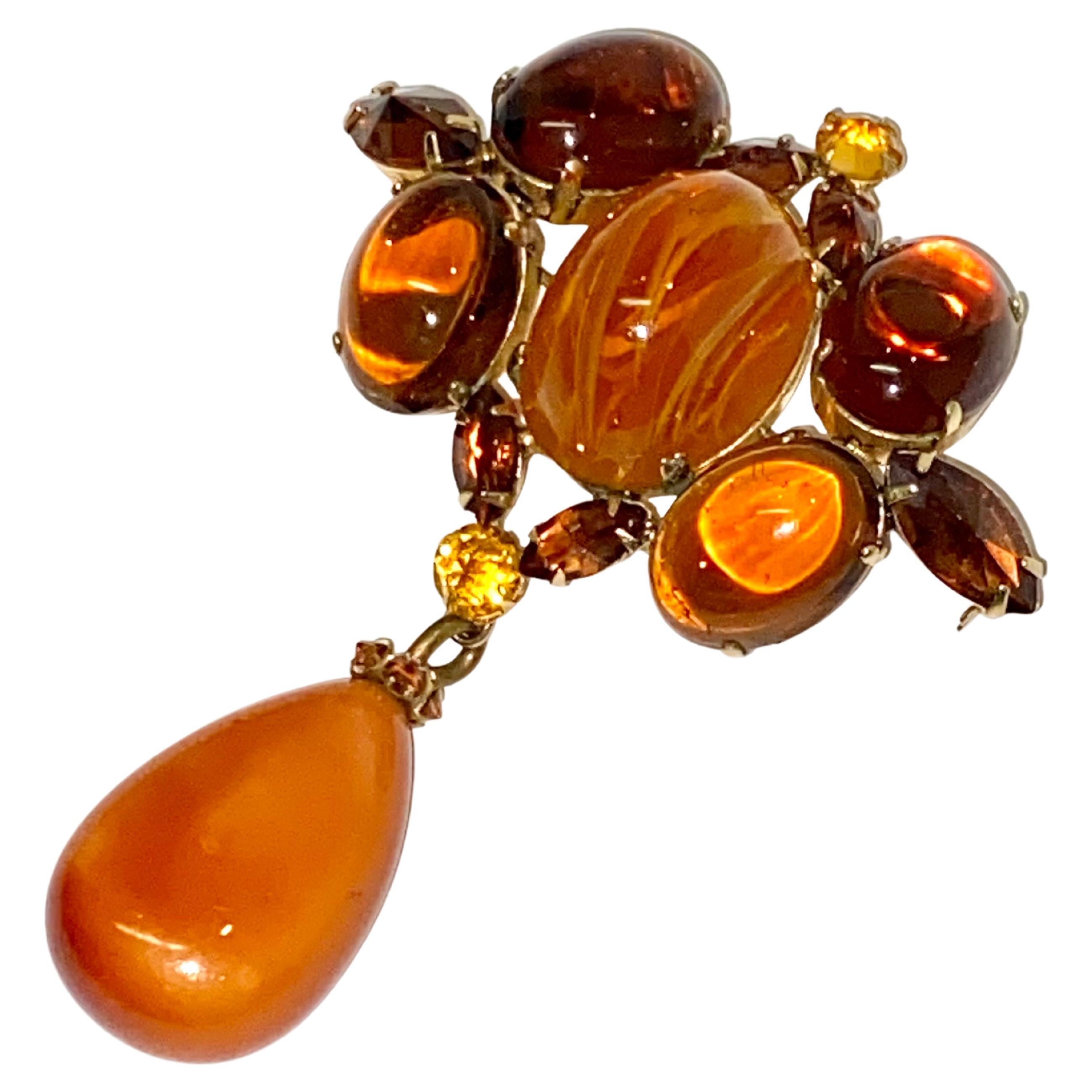 An absolutely stunning and rare color combination Schreiner, New York brooch from the 1950s. The brooch is unique in its use of amber brown and honey caramel color un-foiled glass cabochon stones. The oval glass center stone, measuring .96 of an