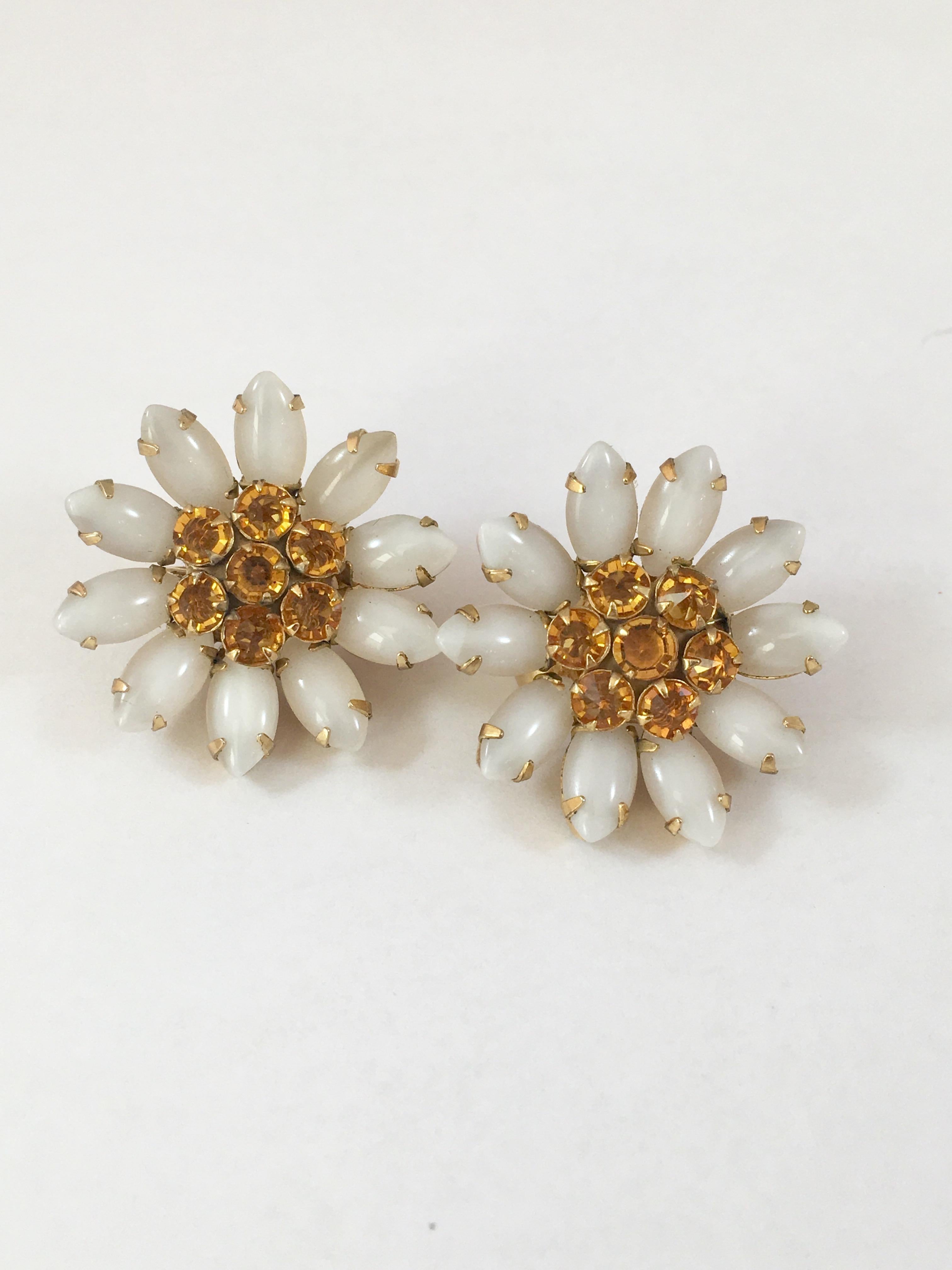 1960s flower clip-on earrings by Schreiner New York. These fun earrings have dark yellow centers consisting of crystals set in the reverse (a Schreiner signature) and white glass petals. They measure 1 1/8 inches in diameter and are signed