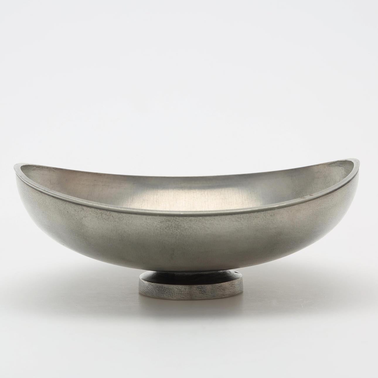 Un bol raffiné en étain brossé du milieu du siècle dernier, conçu et fabriqué par Schreuder & Olsson, Suède, vers 1963. Cette pièce élégamment minimaliste présente une forme semi-ovale légèrement incurvée, surélevée sur une base arrondie, mettant en