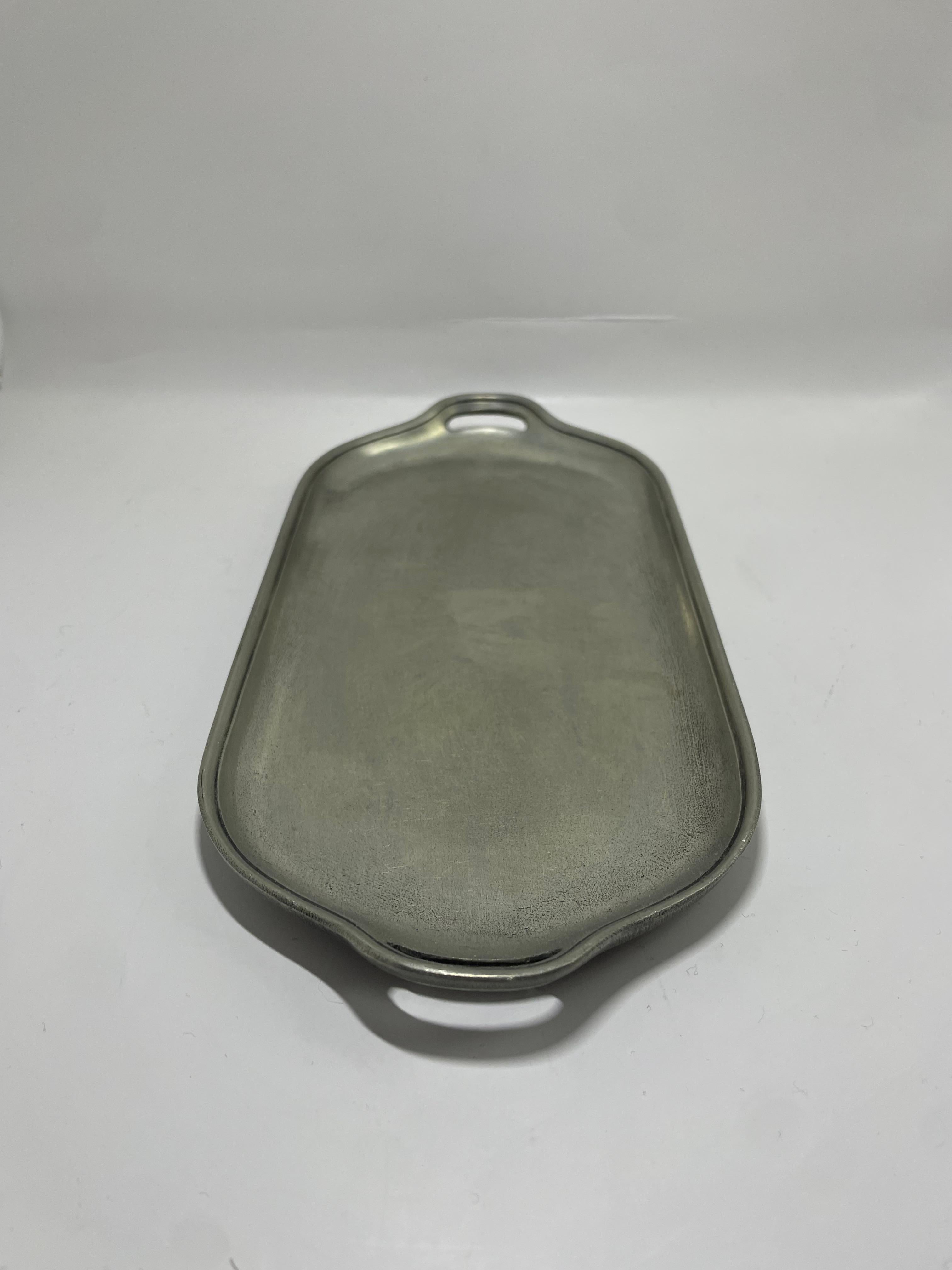 Una elegante y refinada bandeja sueca de peltre de Schreuder & Olsson, que muestra la intemporal artesanía escandinava. Esta elegante pieza de servicio presenta una forma rectangular suavemente curvada con asas integradas en cada extremo, lo que