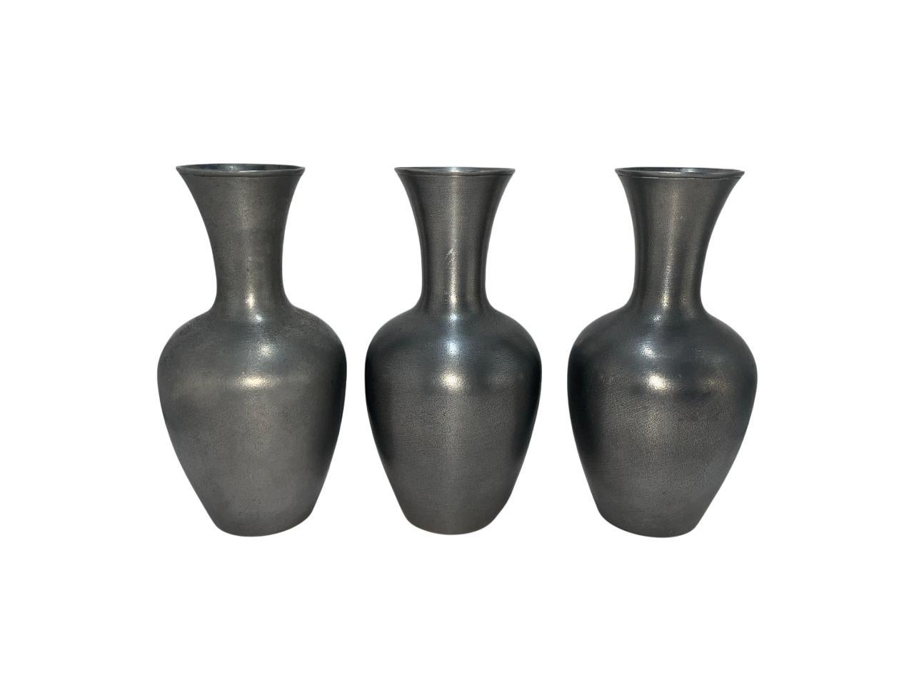 A refined and minimalist set of three pewter vases designed by Schreuder & Olsson, Sweden. These elegant vessels showcase a classic baluster form with softly flaring necks and smooth, matte pewter finish that highlights the sleek silhouette and