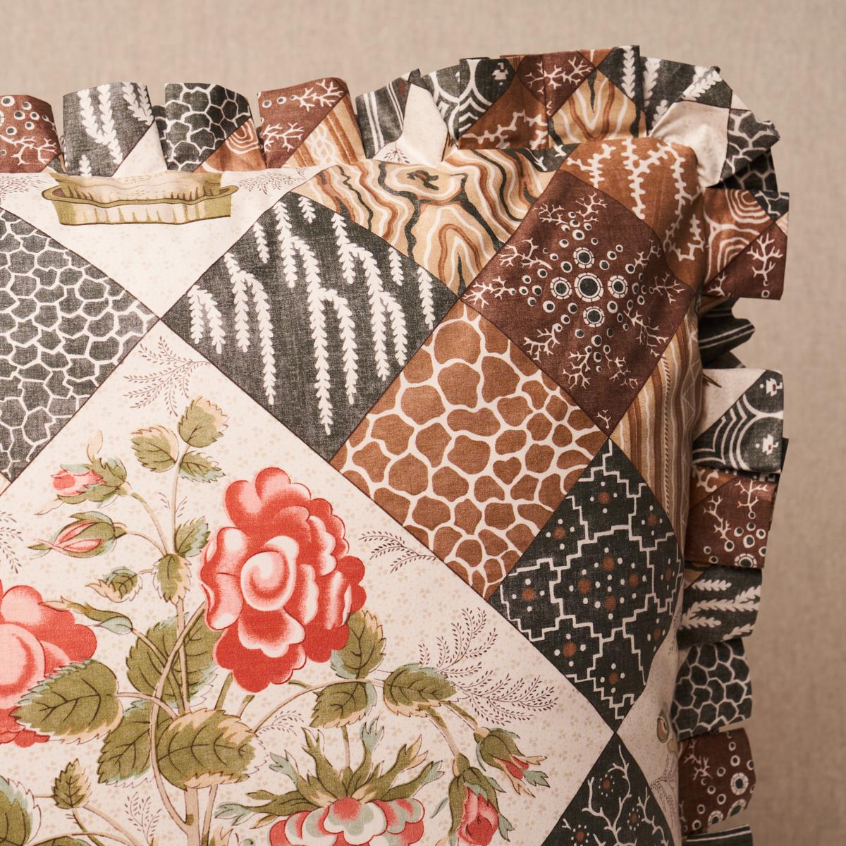 This pillow features Caldwell Patchwork Chintz with a fringe finish. Caldwell Patchwork Chintz in rose-and-chocolate is a trompe l'oeil quilted pattern where lovely floral bouquets are framed by an intricate and charming patchwork of graphic