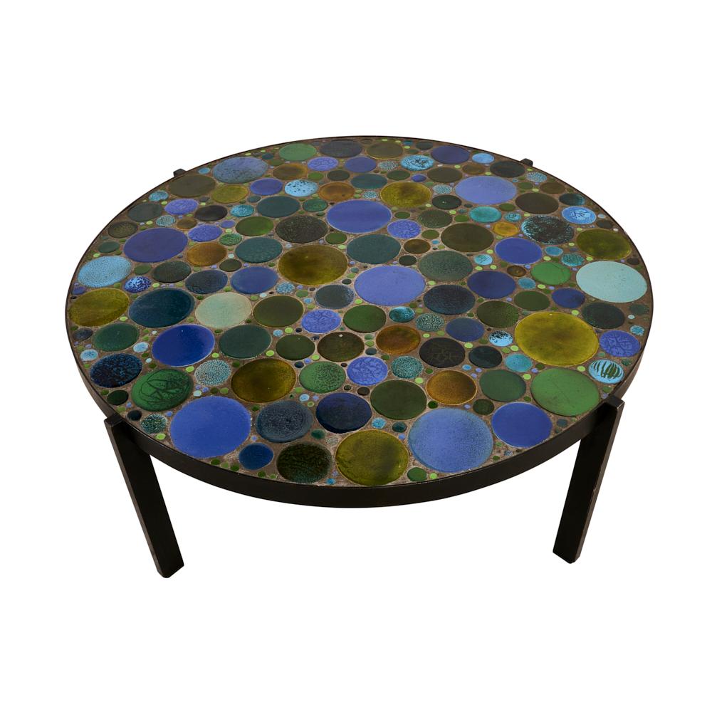 The uniquely round tiles adorning the top of this 1960s French coffee table telegraph fun and provide a joyous visual break from the usual geometric tiles. A circular iron base completes this piece of art in the round. Some slight imperfections can