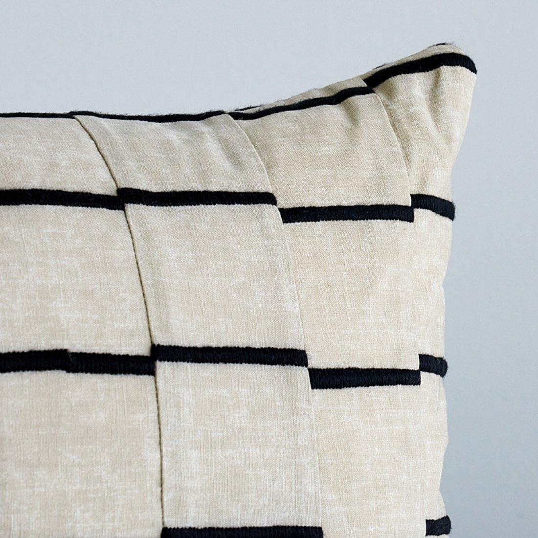 This pillow features Lines by David Kaihoi for Schumacher with a knife edge finish. This deceptively simple-looking fabric is embroidered, then cut into strips and pieced together. The subtle coloring of the ground imparts the instant patina of an