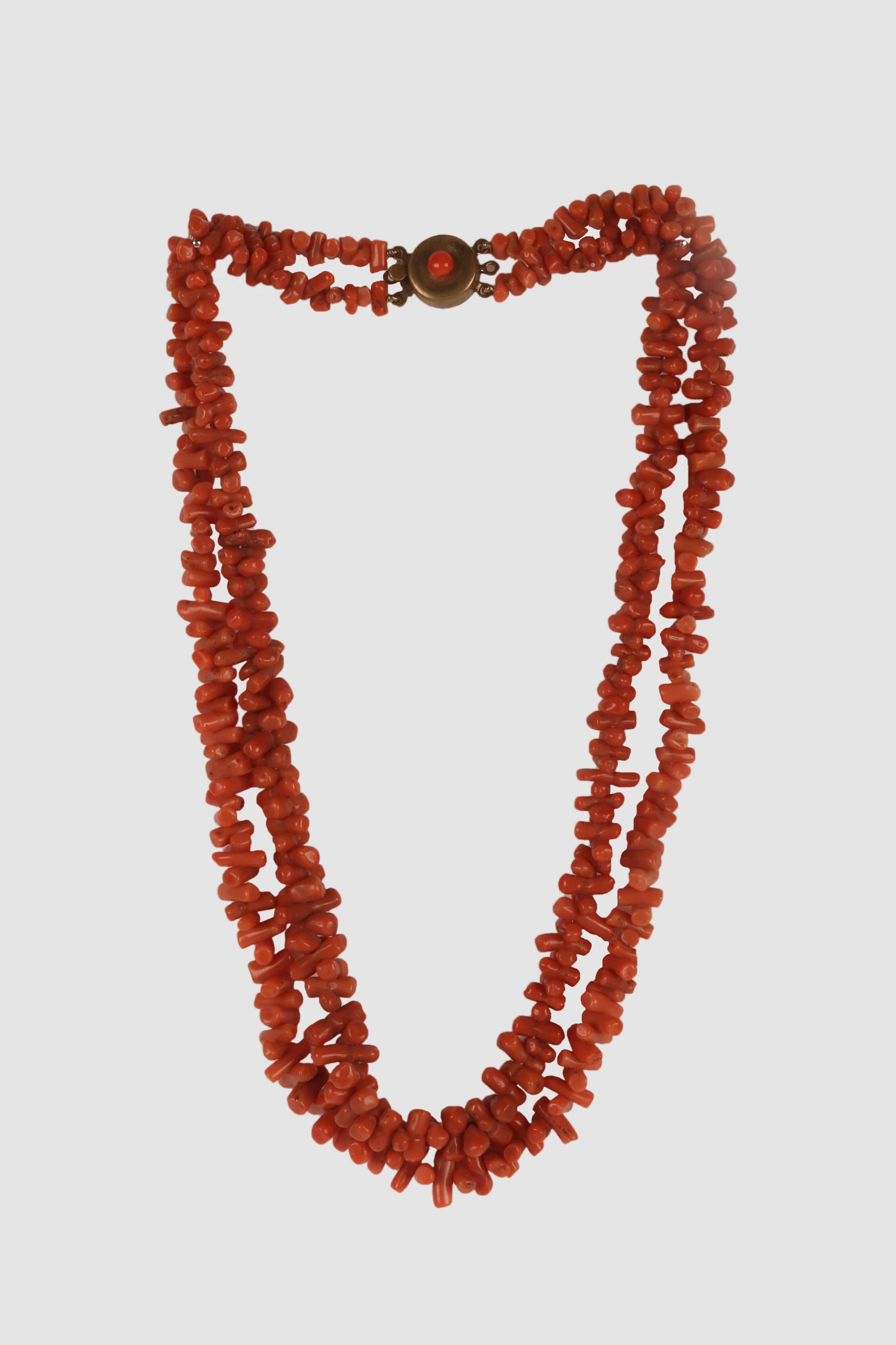 The necklace features a double strand of rod-shaped Sciacca coral elements juxtaposed at right angles in the threading. The round clasp is made of golden metal and features a central Sciacca coral button. Two further lateral hooks probably held a