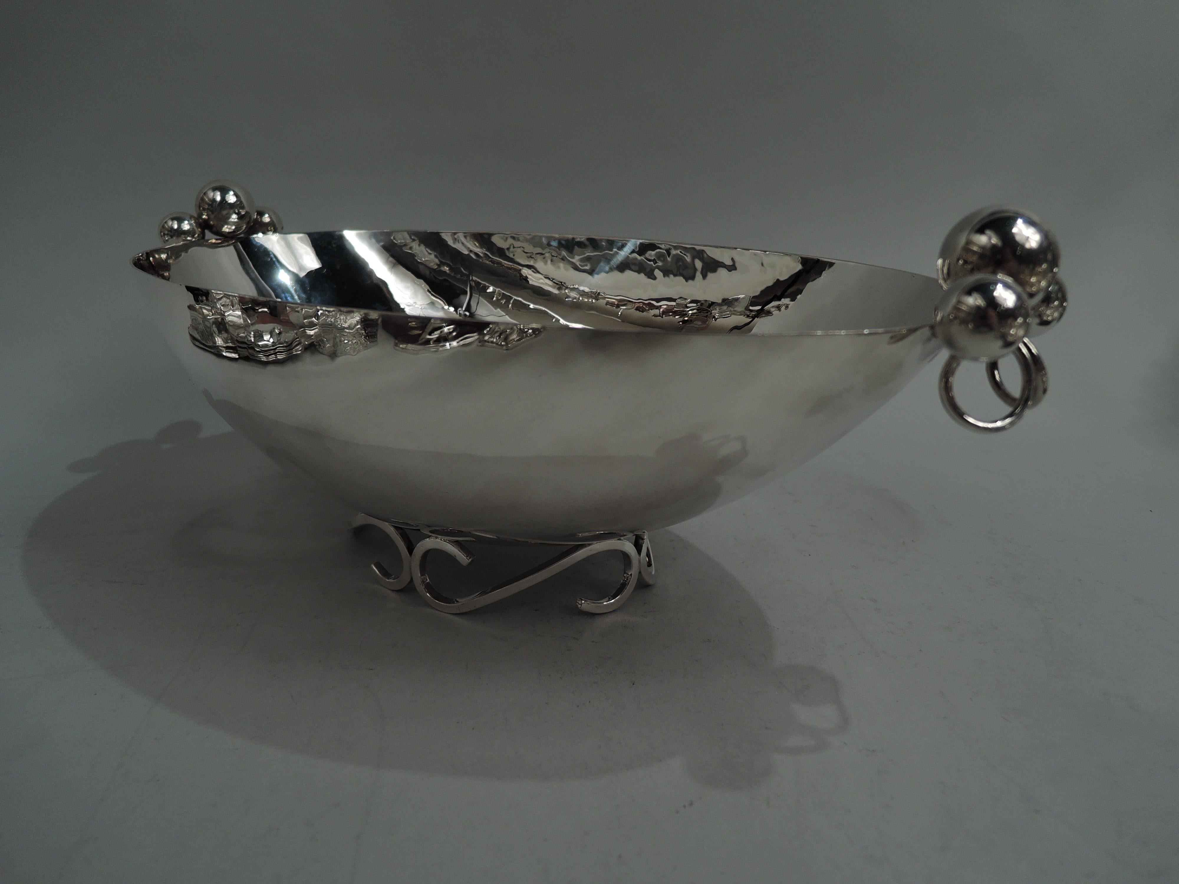 Midcentury Modern sterling silver centerpiece bowl. Made by Alfredo Sciarrotta in Newport. Curved oval on open s-scroll support. Bead and ring ornament mounted to ends. Visible hand hammering. Marked “Sciarrotta / Hand Made / Sterling / 117”.
