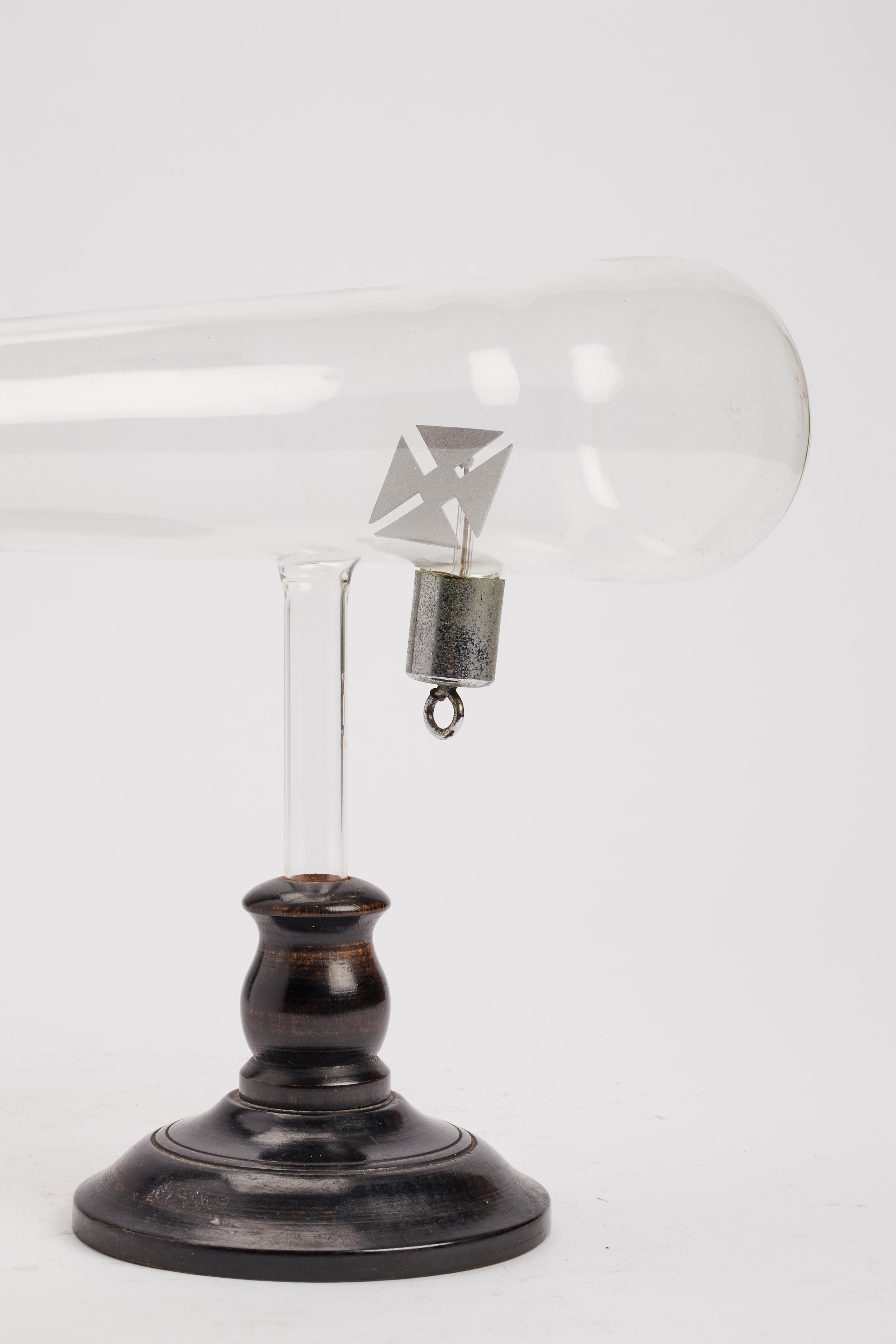 Blown glass scientific instrument. A fine example of Crookes tube with Maltese cross, the precursor of the cathode tube. It demonstrates the rectilinear motion of the rays so that the interposed elements generate shadows. Painted wood base, black