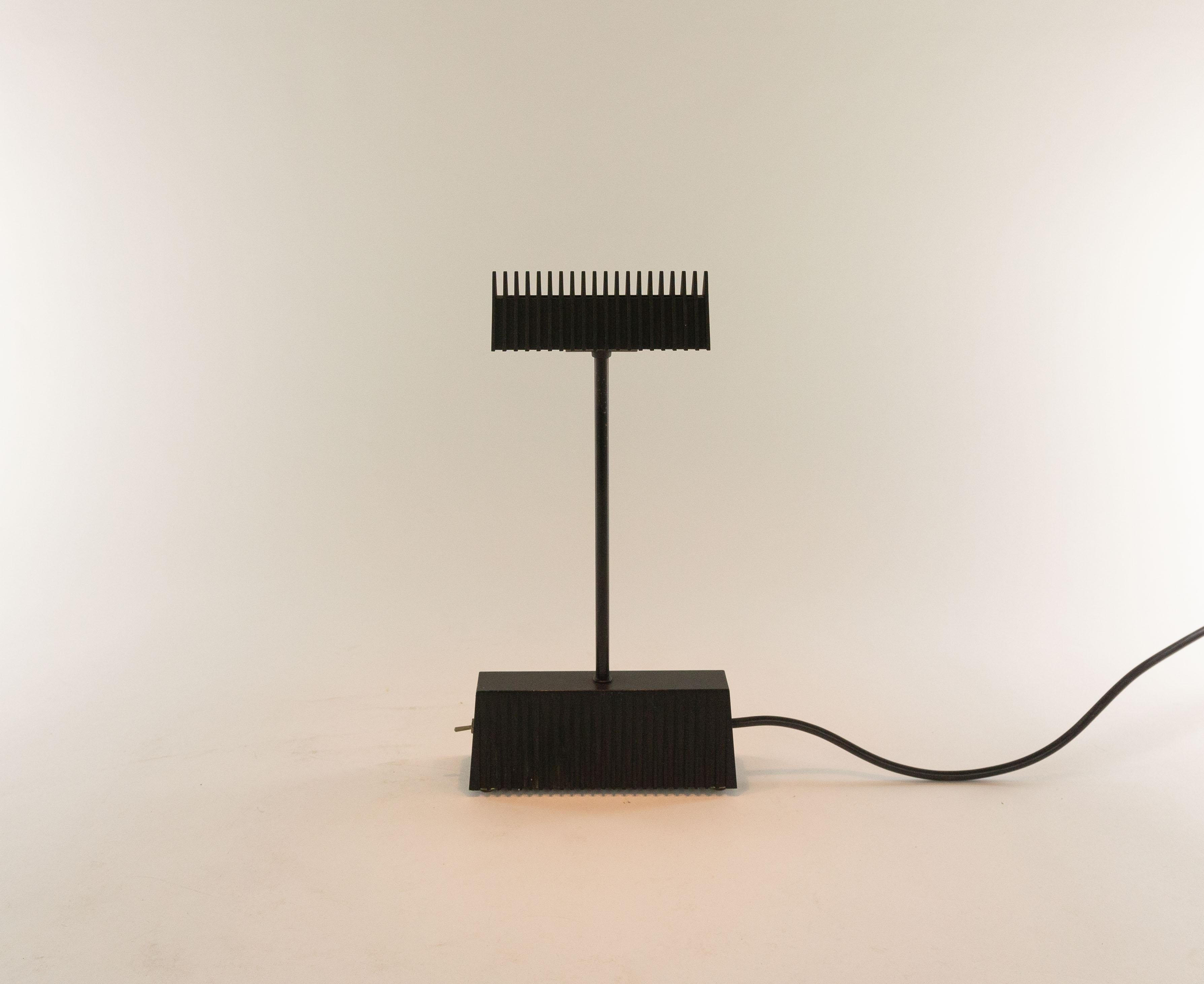 Black Scintilla table lamp, designed in 1984 by Piero Castiglioni for Fontana Arte.

The structure of this table lamp is made from grey die-cast anodized aluminium. In addition to aesthetic beauty, the ribbed surface prevents heat dissipation