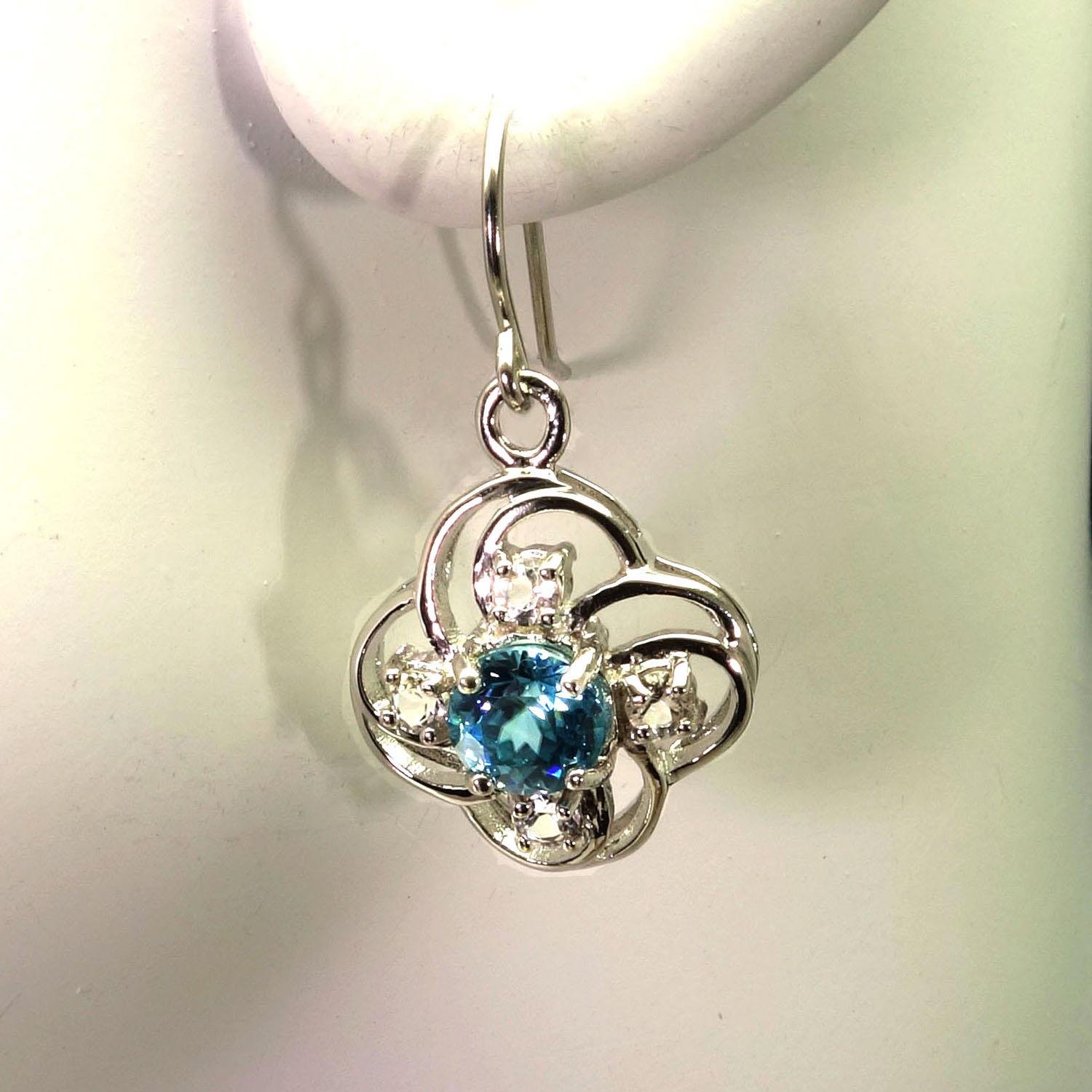 These unique earrings are perfect to wear while you're teleconferencing!  And, they are available for immediate shipment.
Earrings of Swirling Sterling Silver Flower motifs featuring sparkling Blue Cambodian Zircons. The round 2.8ct Blue Zircons are