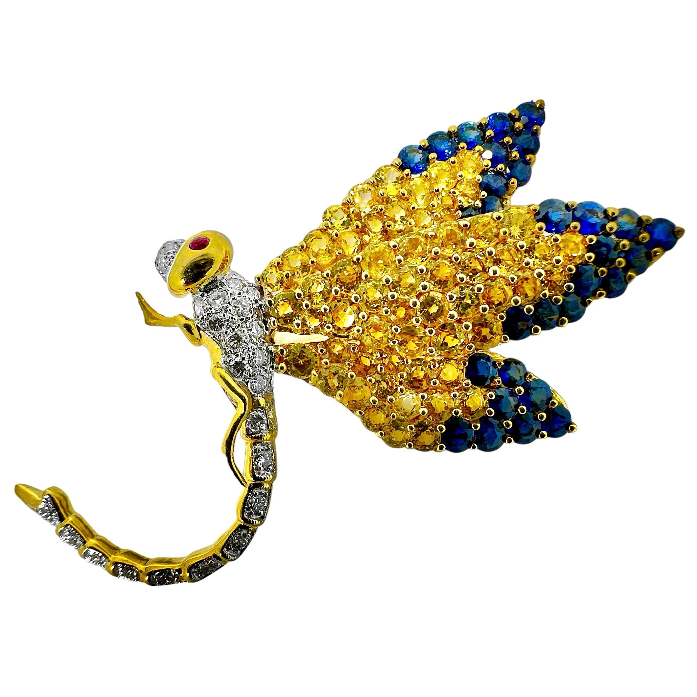 This life like characterization of a dragonfly in flight is lavishly embellished with over 130 round faceted golden and blue sapphires as well as a number of round brilliant cut diamonds. Total approximate sapphire weight is 7.00ct and total