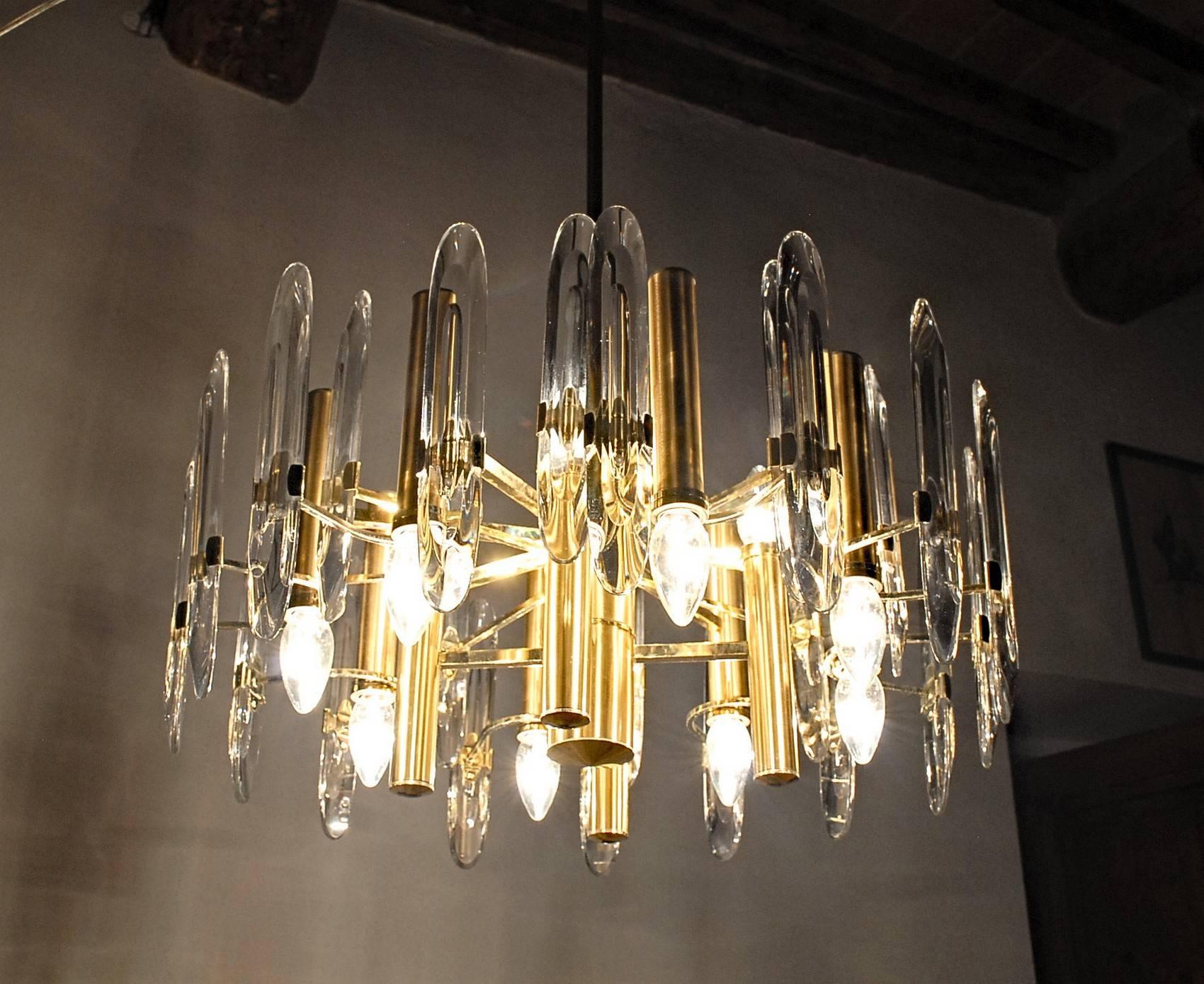 Twelve light chandelier from Gaetano Sciolari production made for Stilkronen, Italy, 1970s.
Six lights down and six lights up. Brass gold-plated. Transparent elements in Led Crystal.

This is an interesting version of the Sciolari's production.