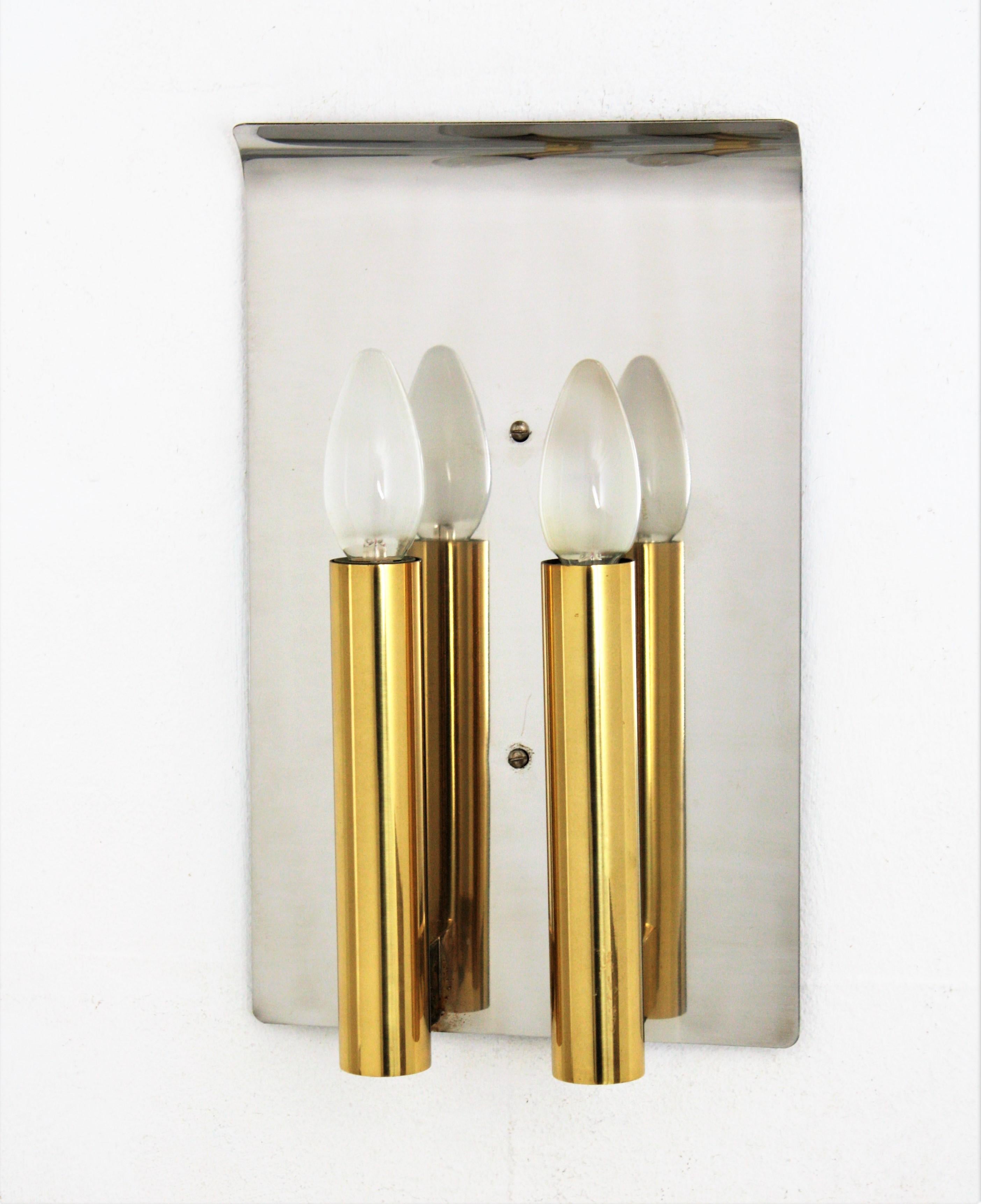 Elegant two-light modernist brass and steel wall sconce. Attributed to Gaetano Sciolari. Italy, 1960s
This wall light features a stainless steel back panel with curved ending top holding two polished brass cylinder shaped candelabra holders.
Very