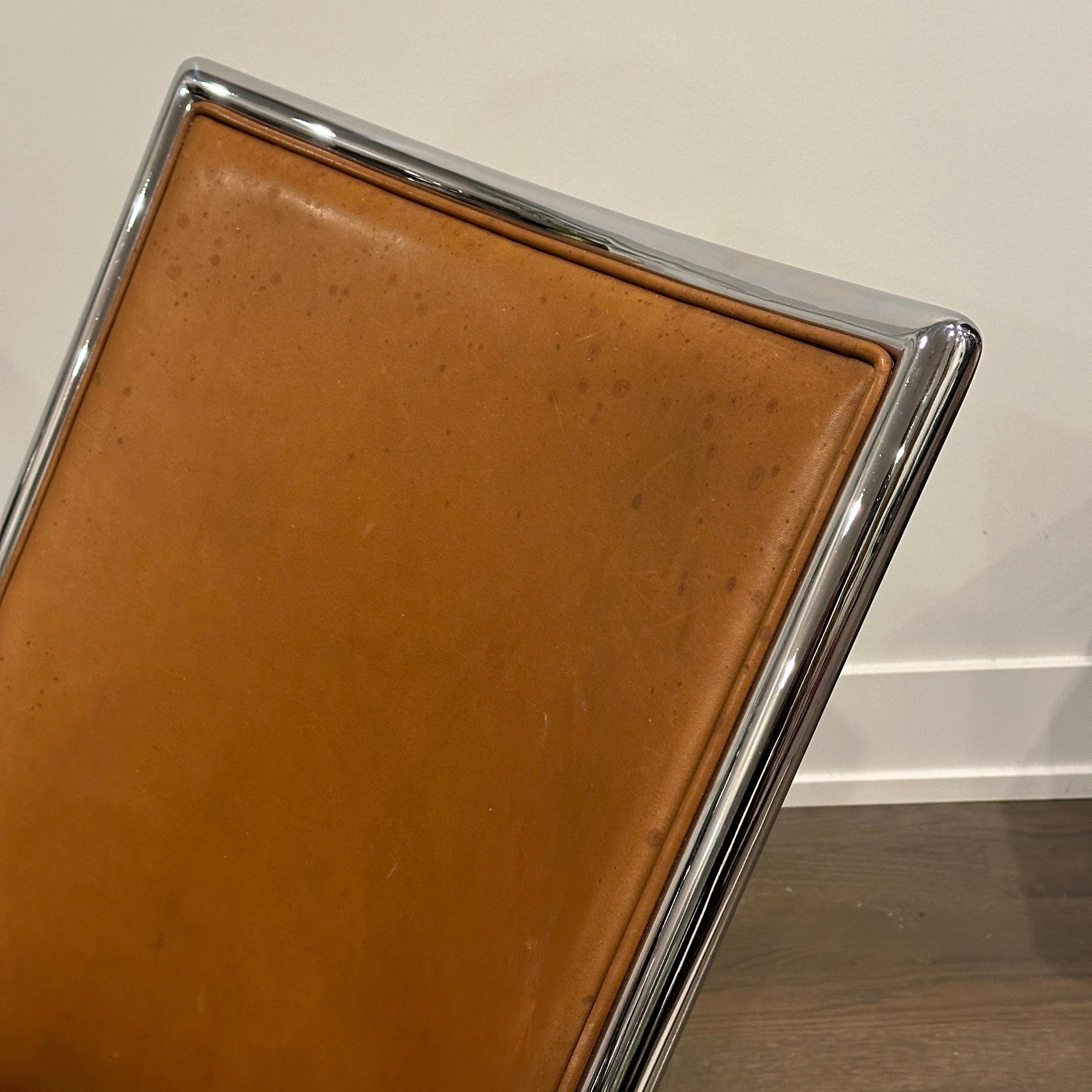 Silla de tijera con estructura cromada del diseñador Ward Bennett, en cuero marrón, la pieza está marcada.

