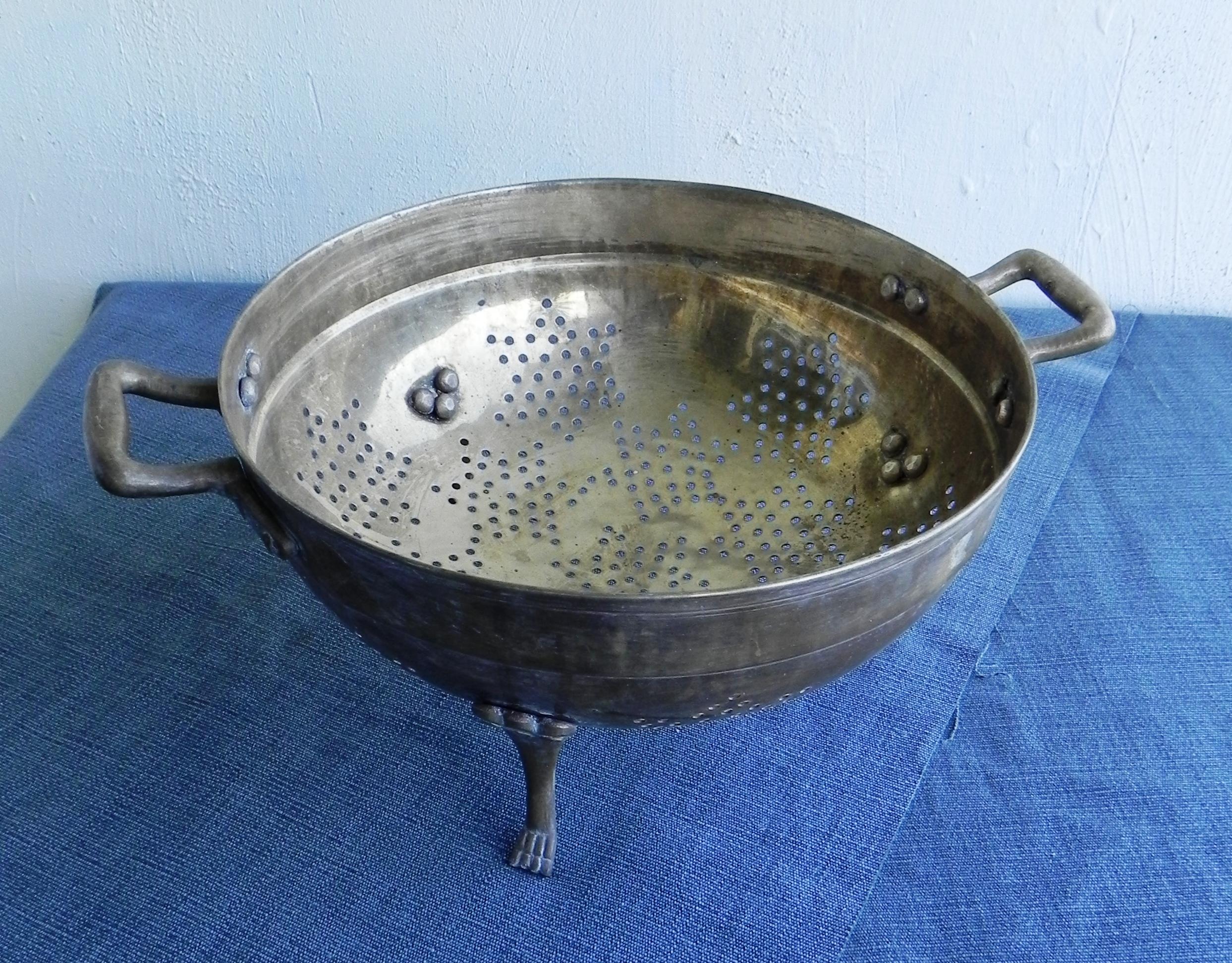 1 solid brass colander. dates from the 1970s. 2 decorated and shaped handles. 3 feet with paw finial. circle diameter 33 cm. handles excluded. sturdy and solid, usable in the kitchen or as decoration. should be cleaned well with special metal paste.
