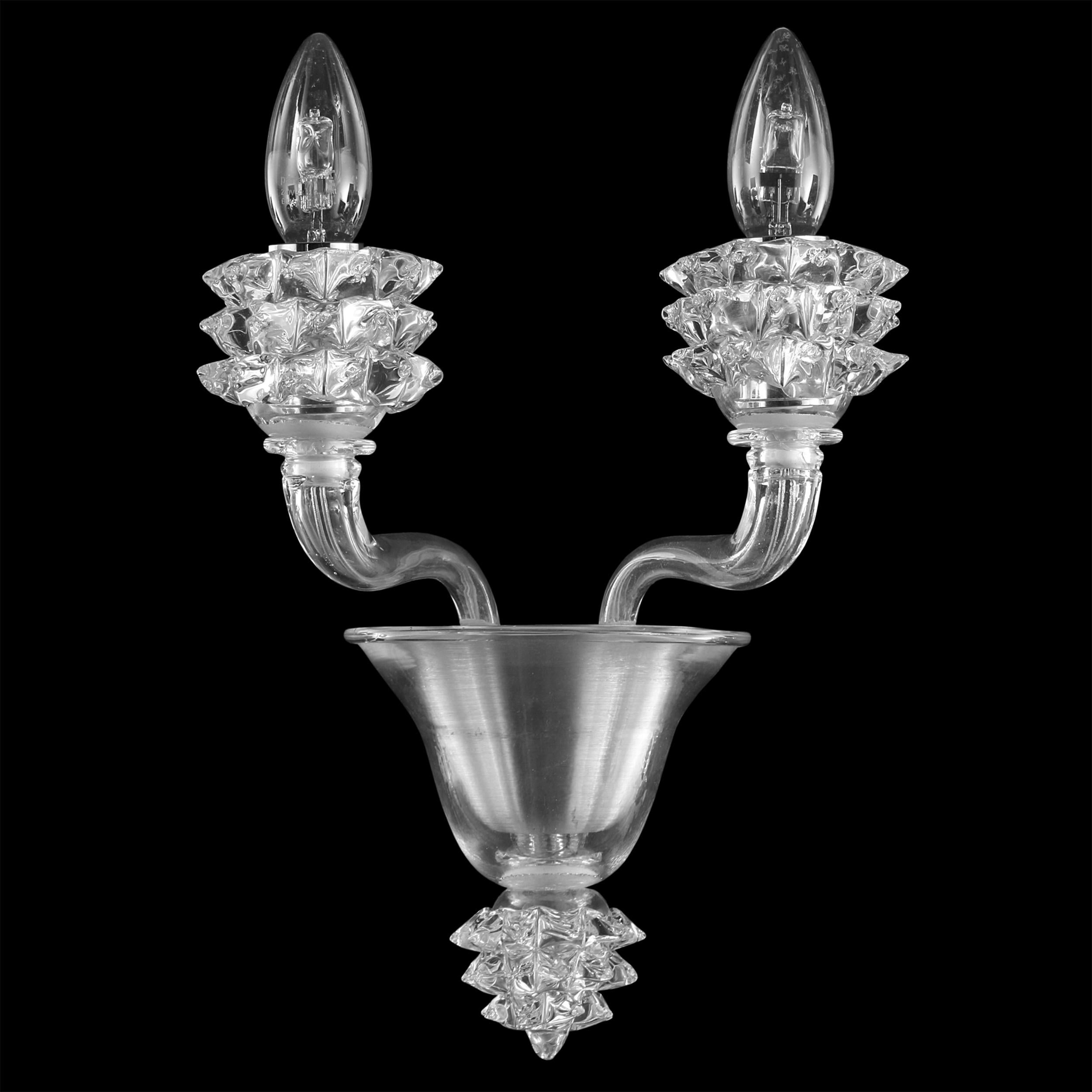The Diamante sconce with 2 arms in clear encased Murano glass and clear details is a well proportioned product.
The glass of the arms is smooth. The standout elements of this sconce are the cups, which are created using a complex manufacturing
