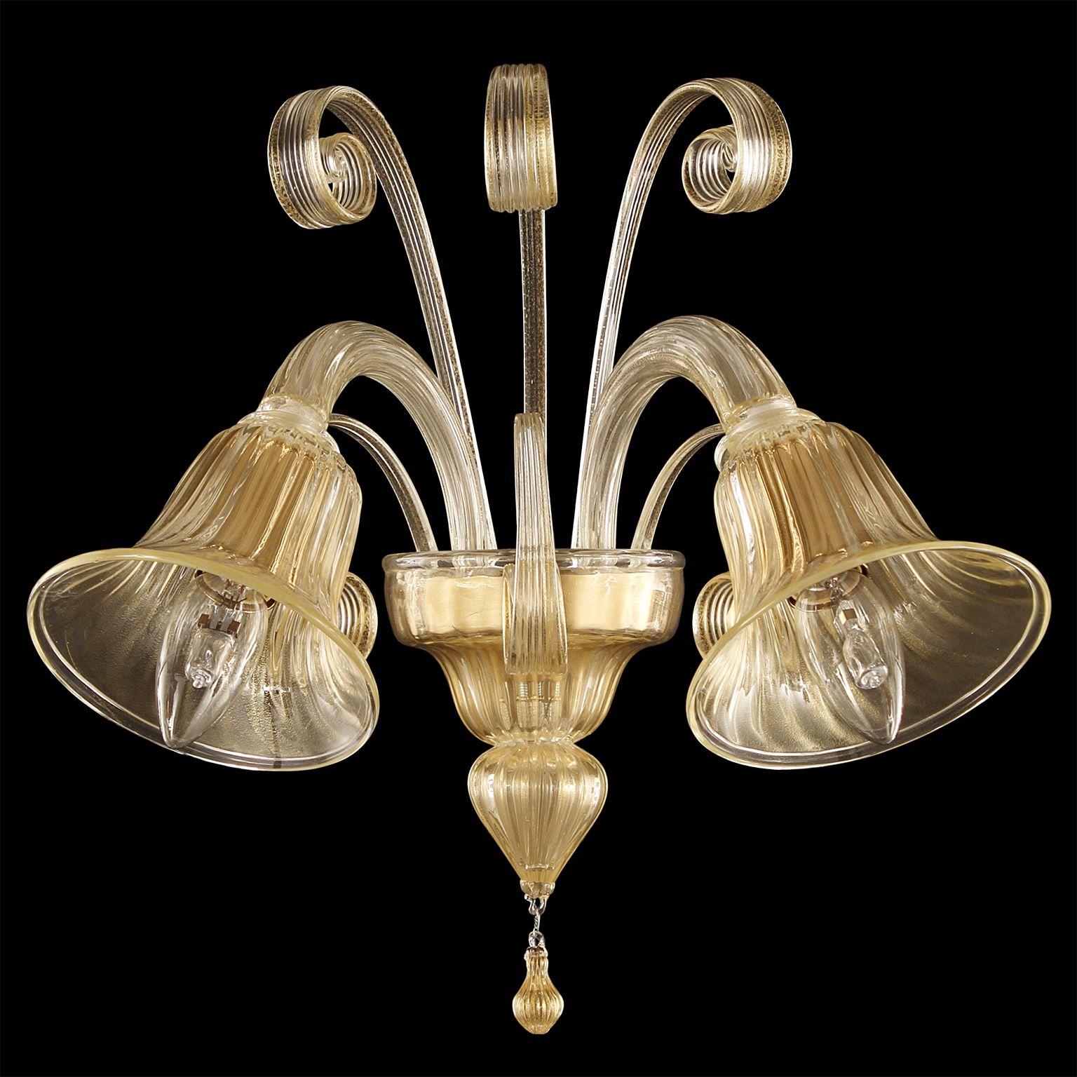 Capriccio by Multiforme is a sconce with 2 downward lights golden leaf artistic glass and curly ornamental elements.
Inspired by the Classic Venetian tradition it is characterized by a central column where many blown glass “pastoral” elements are